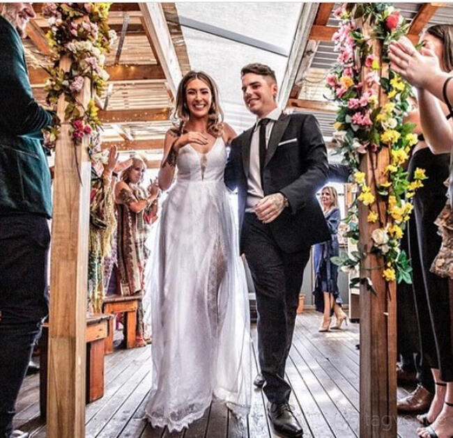 A terrace bar with wooden decking, floral decorations, and a covered roof at The Purple Emerald Lounge Bar.
