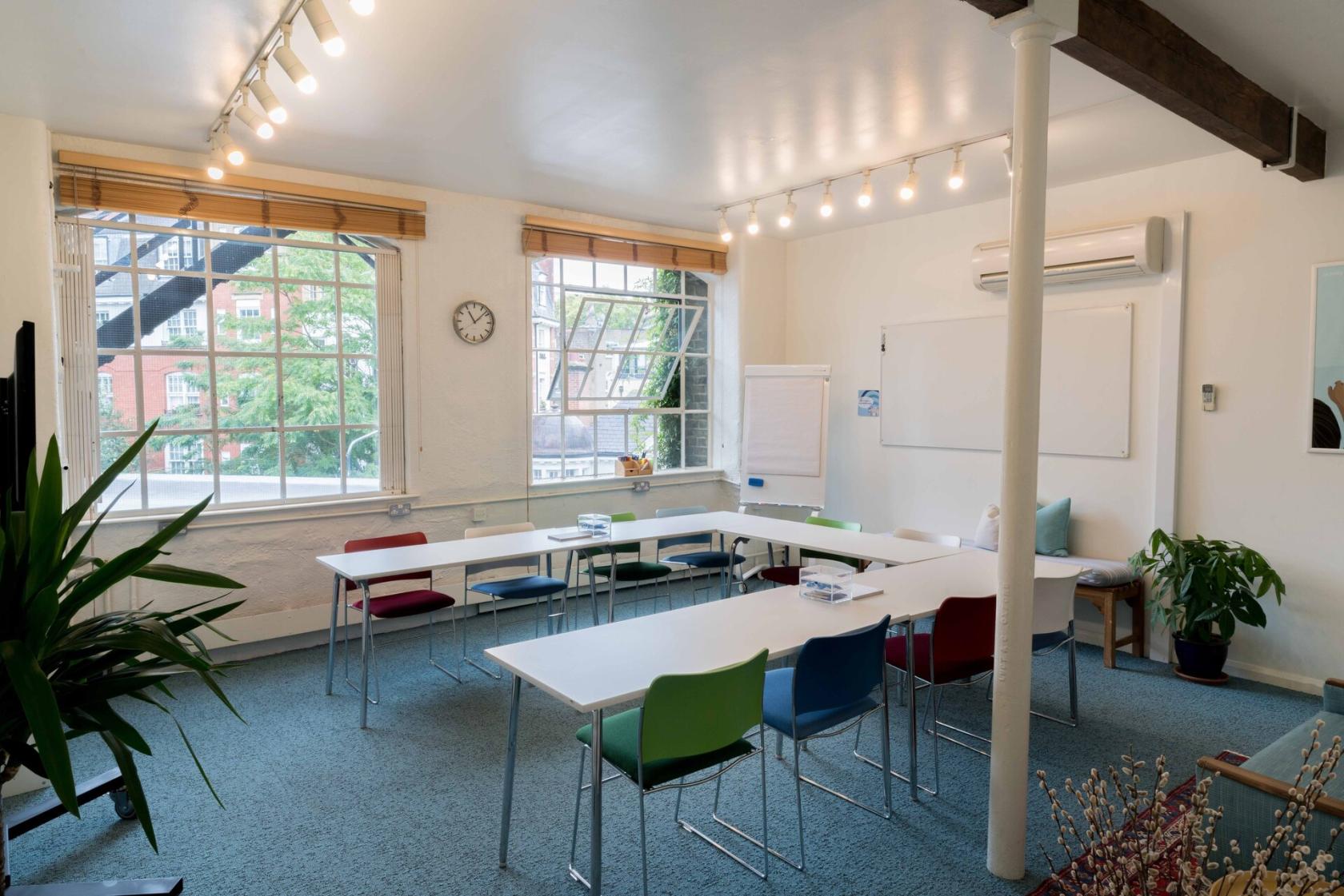 An event venue with large windows, whiteboards, and colorful chairs in Square Room 2 at Wallacespace St Pancras.