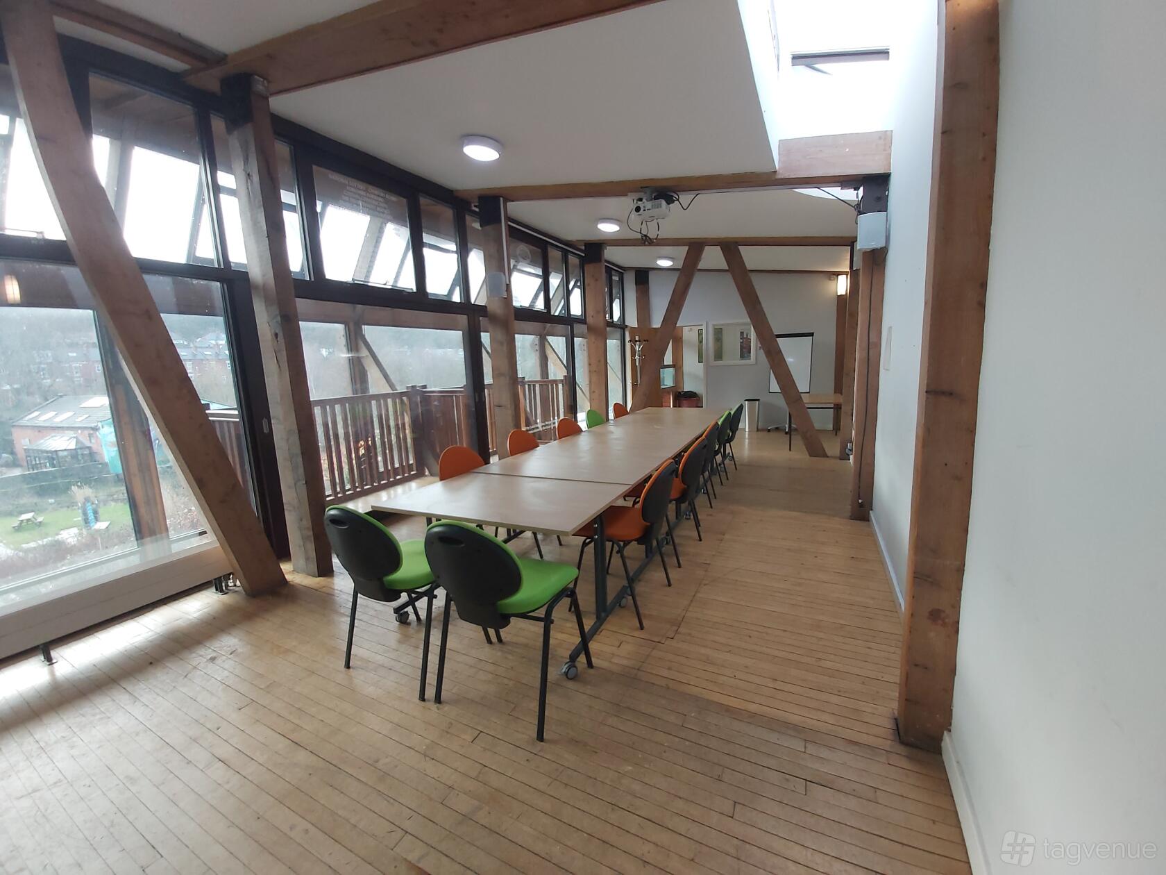 A meeting room with floor-to-ceiling windows, exposed wooden beams, and a long table at Meanwood Valley Urban Farm.