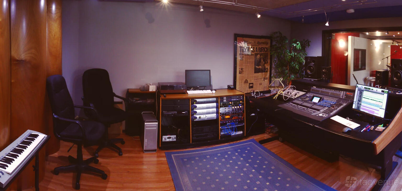 A recording studio with a mixing console, computer workstation, and hardwood floors at Mad Cat.