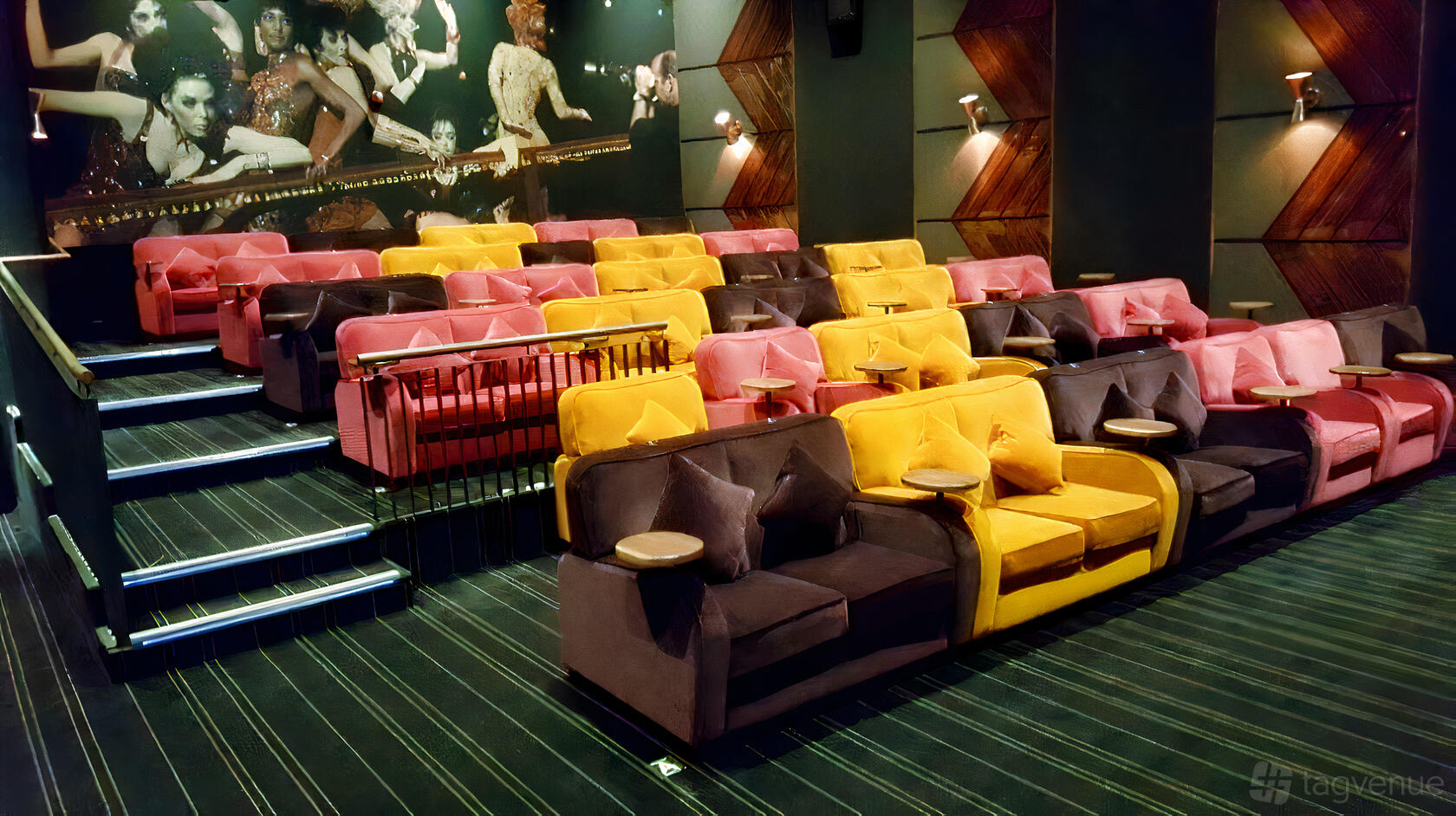 An auditorium with tiered plush seating in yellow and brown, small round tables, and movie mural at Everyman Chelmsford.