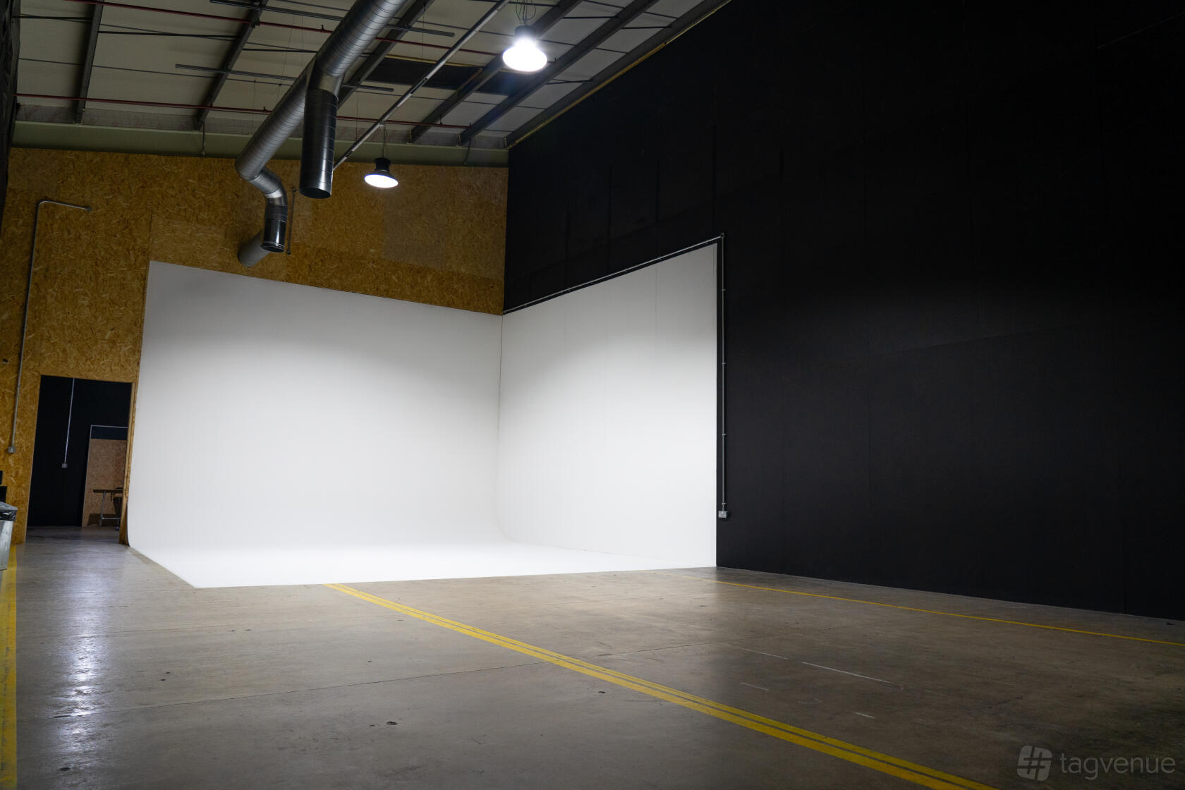 A photo studio with a large white cyclorama wall and exposed ductwork at Un.titled Studio.