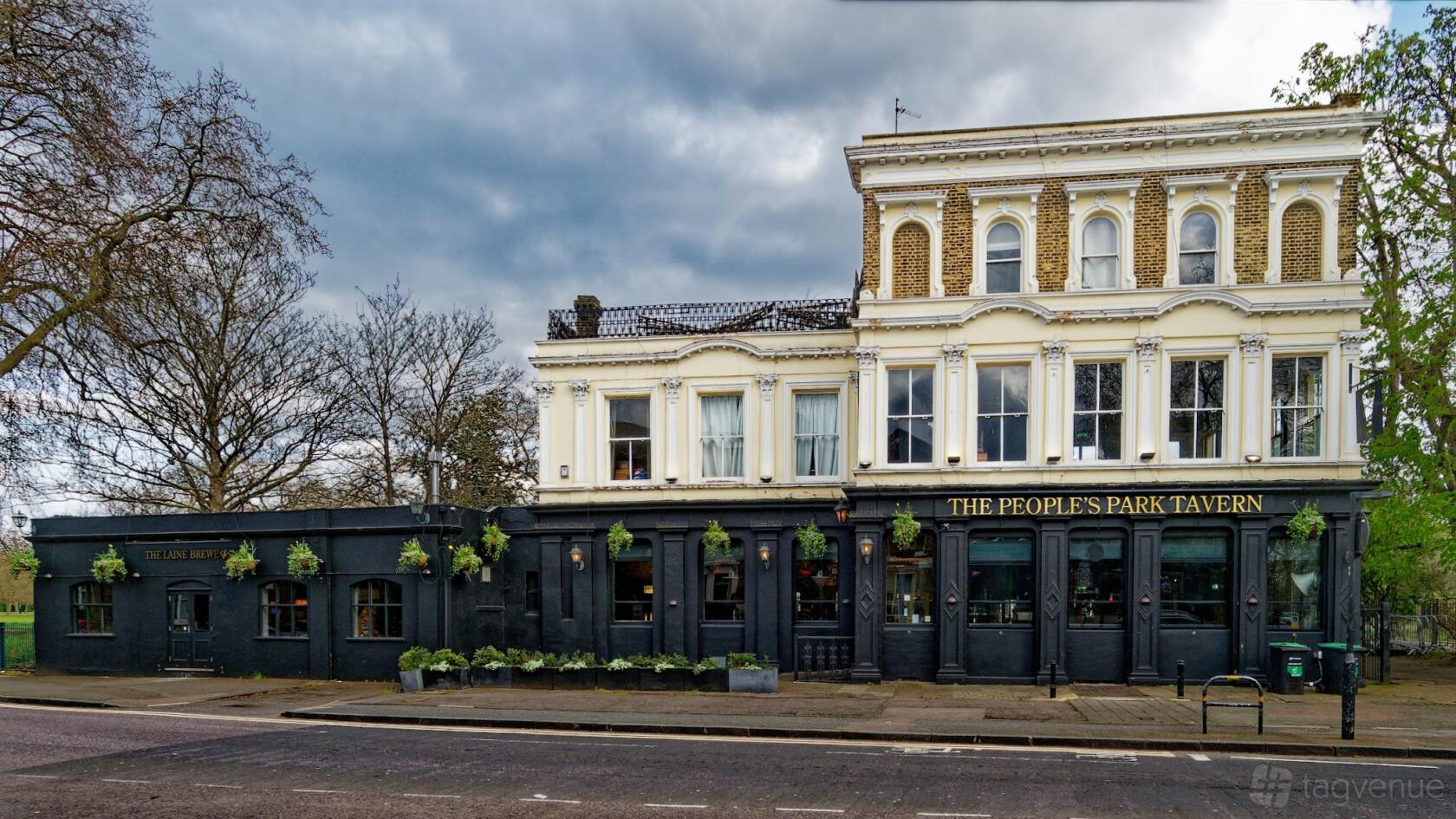 A historic pub with cream and black façade, large windows, and hanging plants at People's Park Tavern.