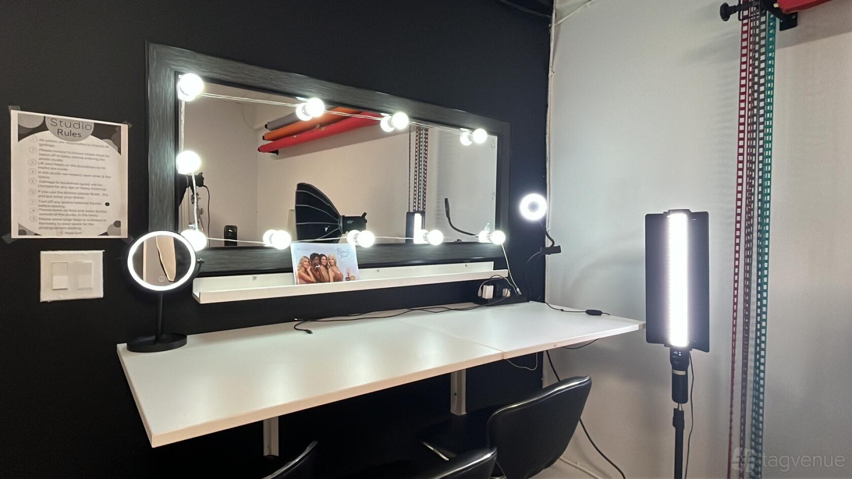 A photo studio with a makeup station featuring a large lighted mirror and studio lighting at Galaxy Studios.