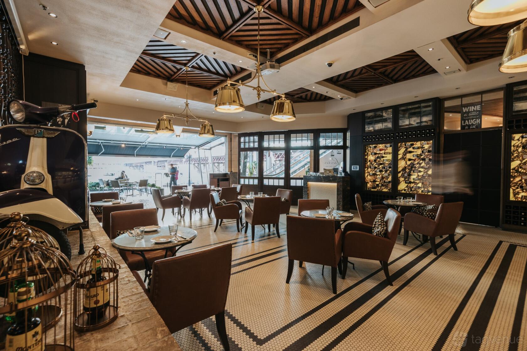 A restaurant with brown leather chairs, patterned tile flooring, and geometric wooden ceiling panels at Baia The Italian.