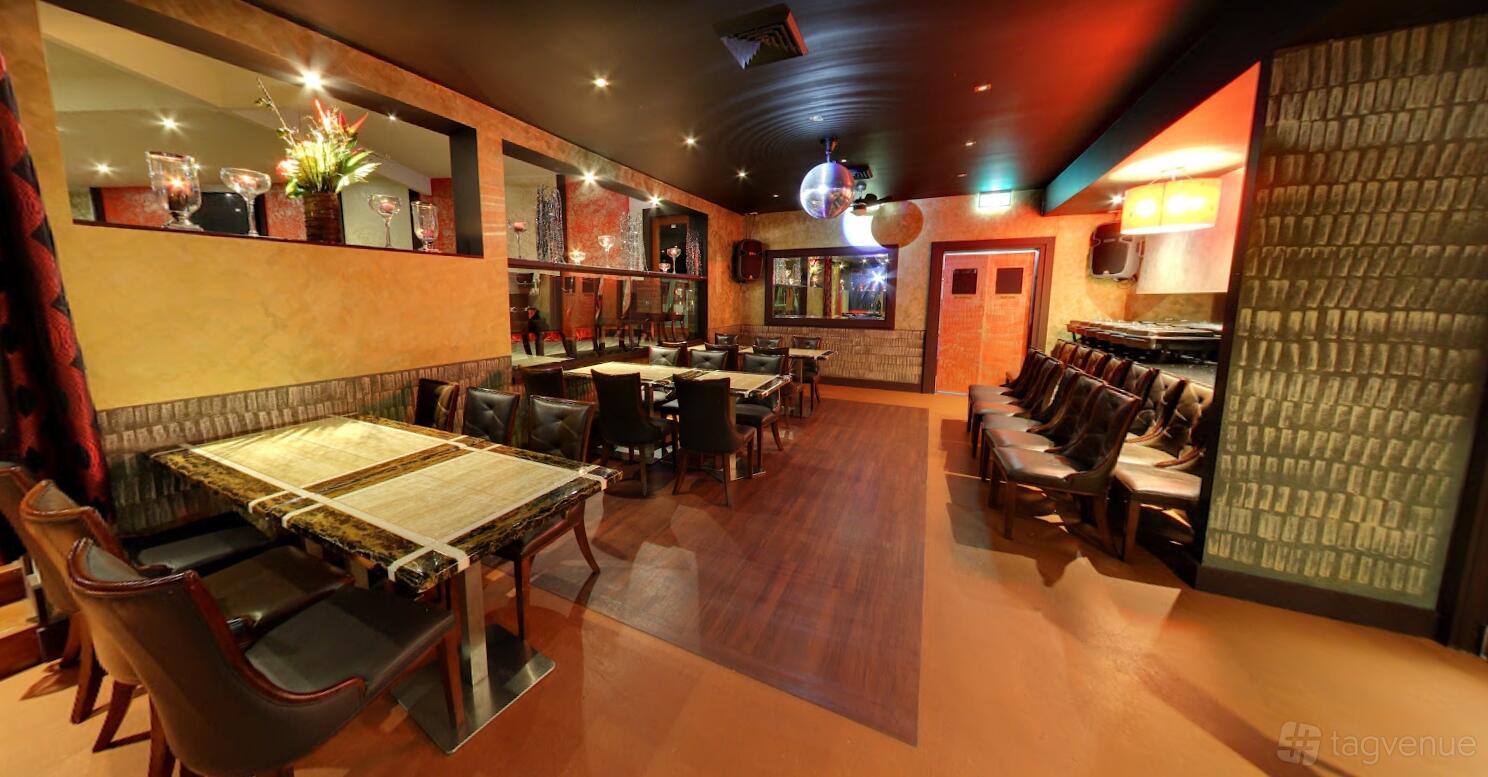 An event space in a restaurant with leather chairs, mirror wall accents, and disco balls at Urban Tadka.