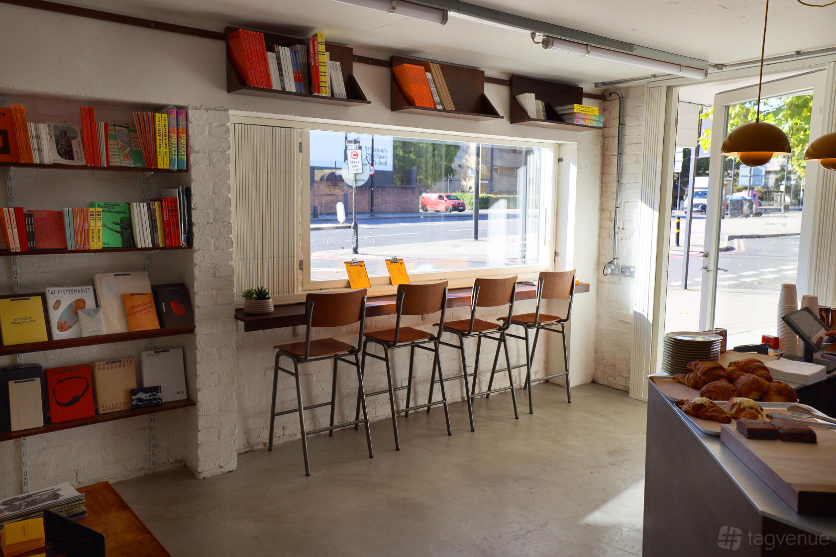 An event venue with large street-facing windows, a high counter with stools, and shelves of books at FormaHQ.