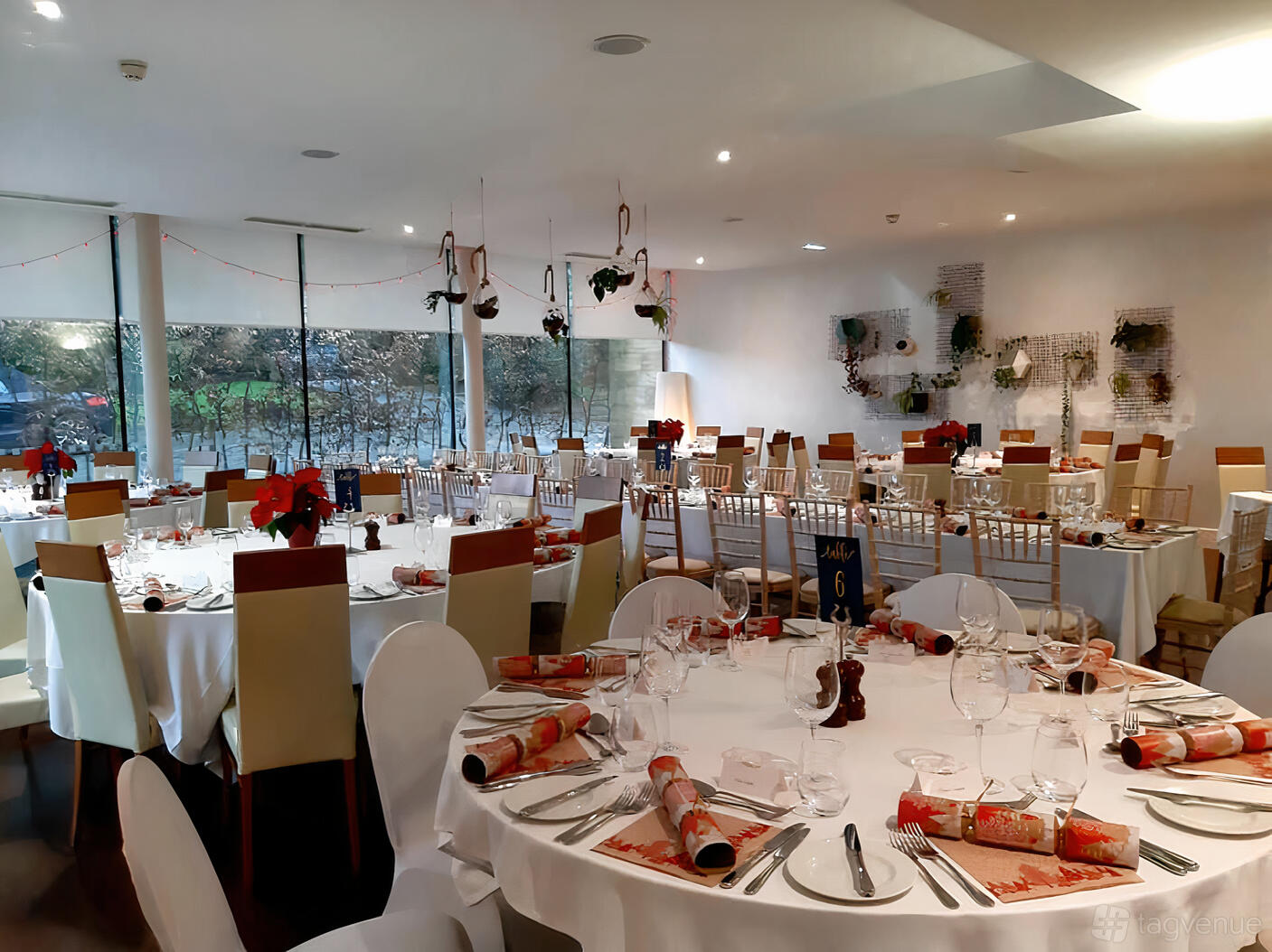 An event space with round tables set with white linens, glassware, and festive decorations at Lanes Hotel.