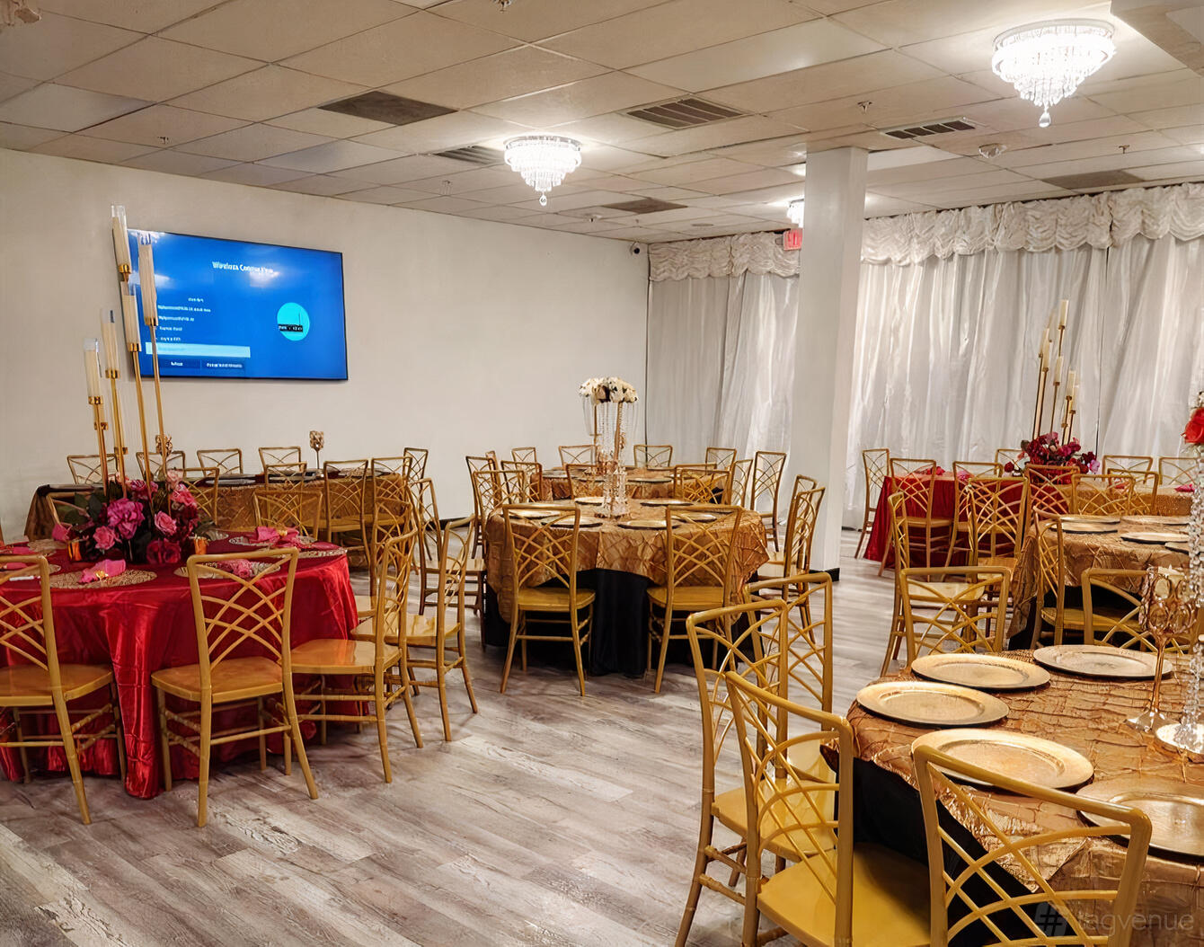 An event venue with round tables, gold chairs, floral centerpieces, and chandeliers at Bliss Pavilion 2.