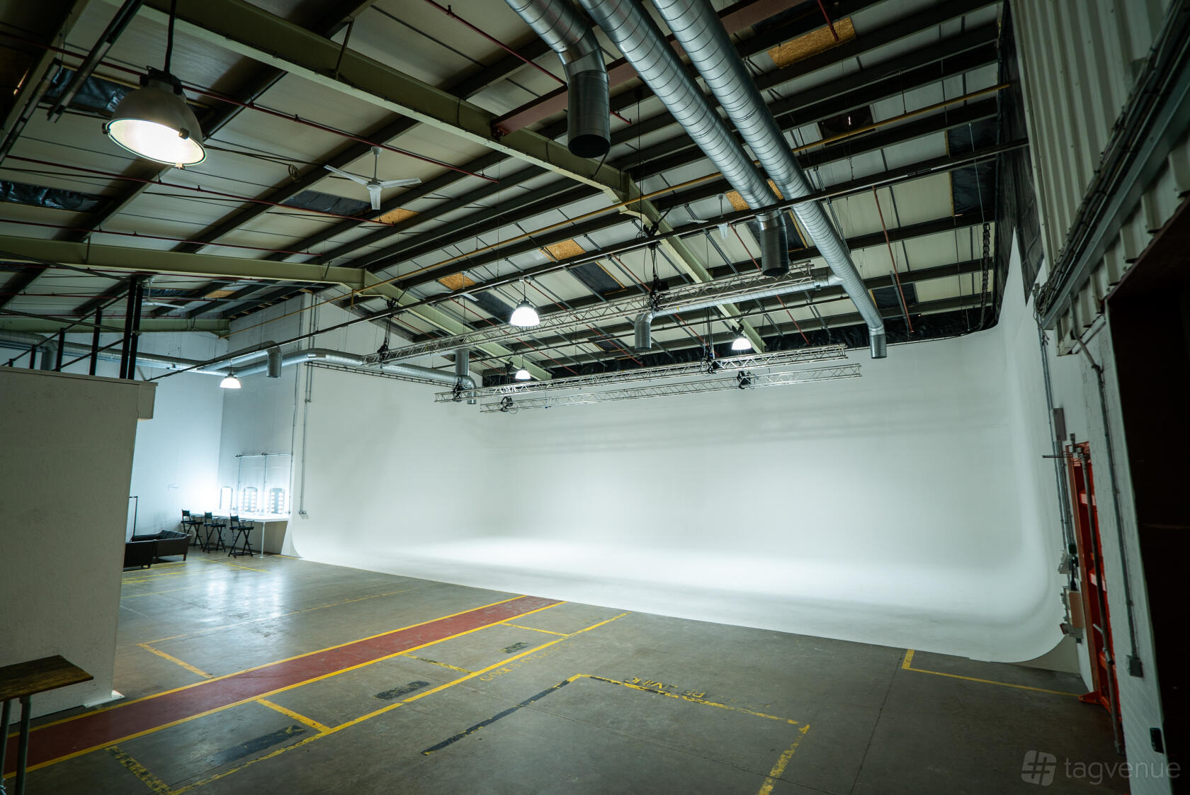 A photo studio with a large white cyclorama wall, exposed ceiling beams, and industrial lighting at Un.titled Studio.
