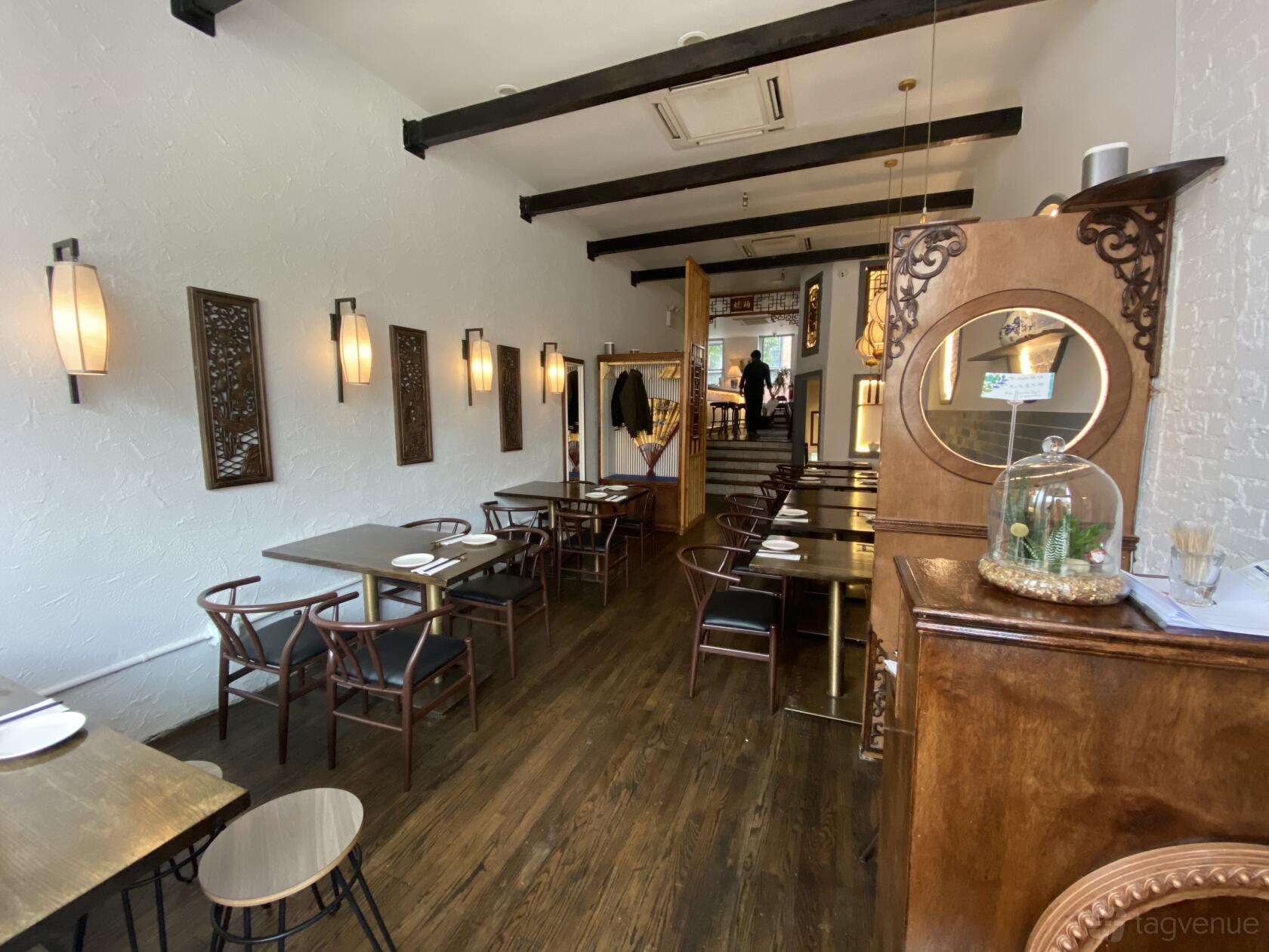 A restaurant event space with dark wood tables, carved wooden decor, and wall-mounted lights at HUPO.