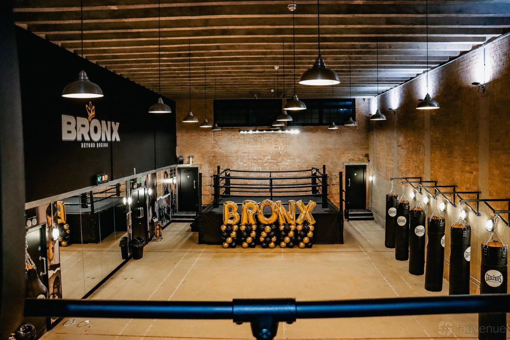 An event venue with a central boxing ring, exposed brick walls, and hanging punching bags at Bronx.