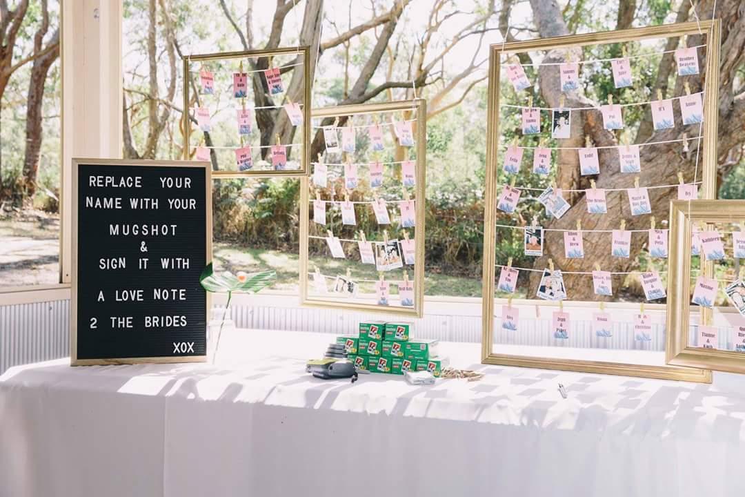 A versatile event space with framed photo displays and a guest sign-in station near large windows at The Retreat Port Stephens.