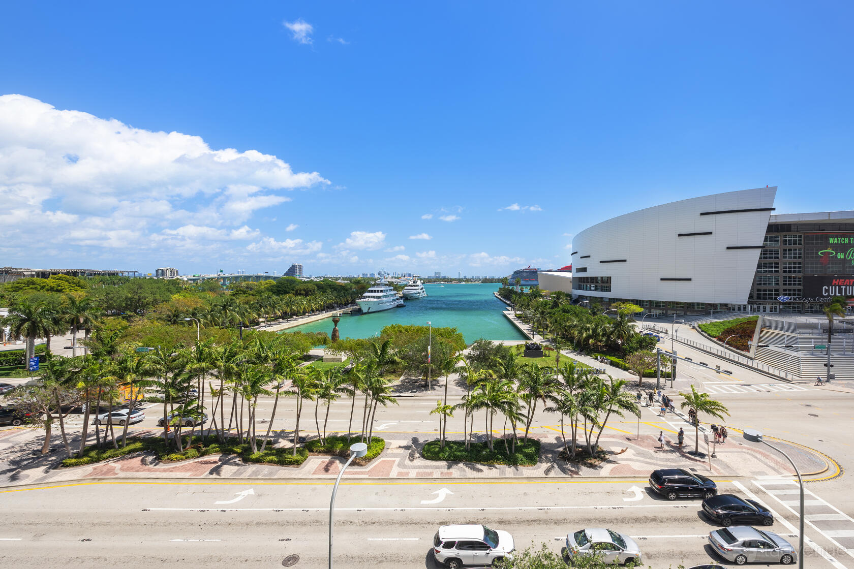 An exterior view of palm-lined streets, waterfront, and a nearby arena by Nimbler Spaces - Miami.