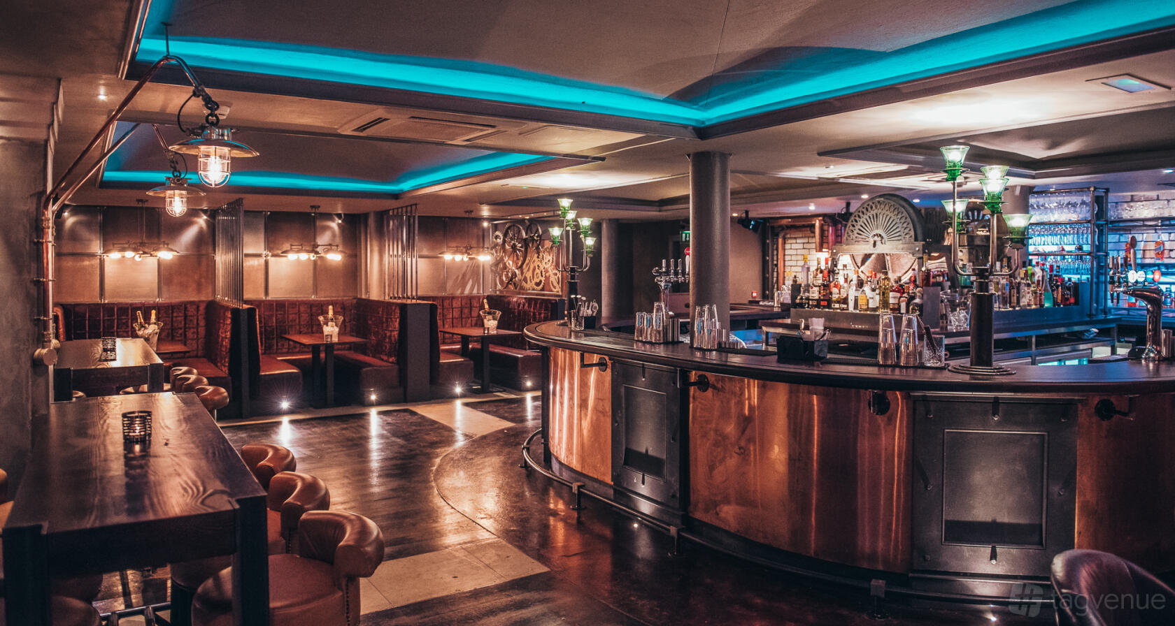 An event space in a restaurant with curved copper bar, leather seating, and blue accent lighting at Arta.
