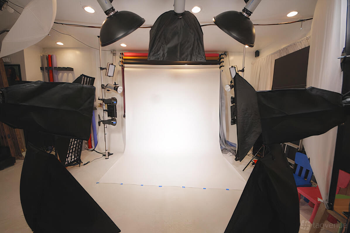 A photo studio with a white backdrop, multiple softbox lights, and colored paper rolls at Coche Productions.