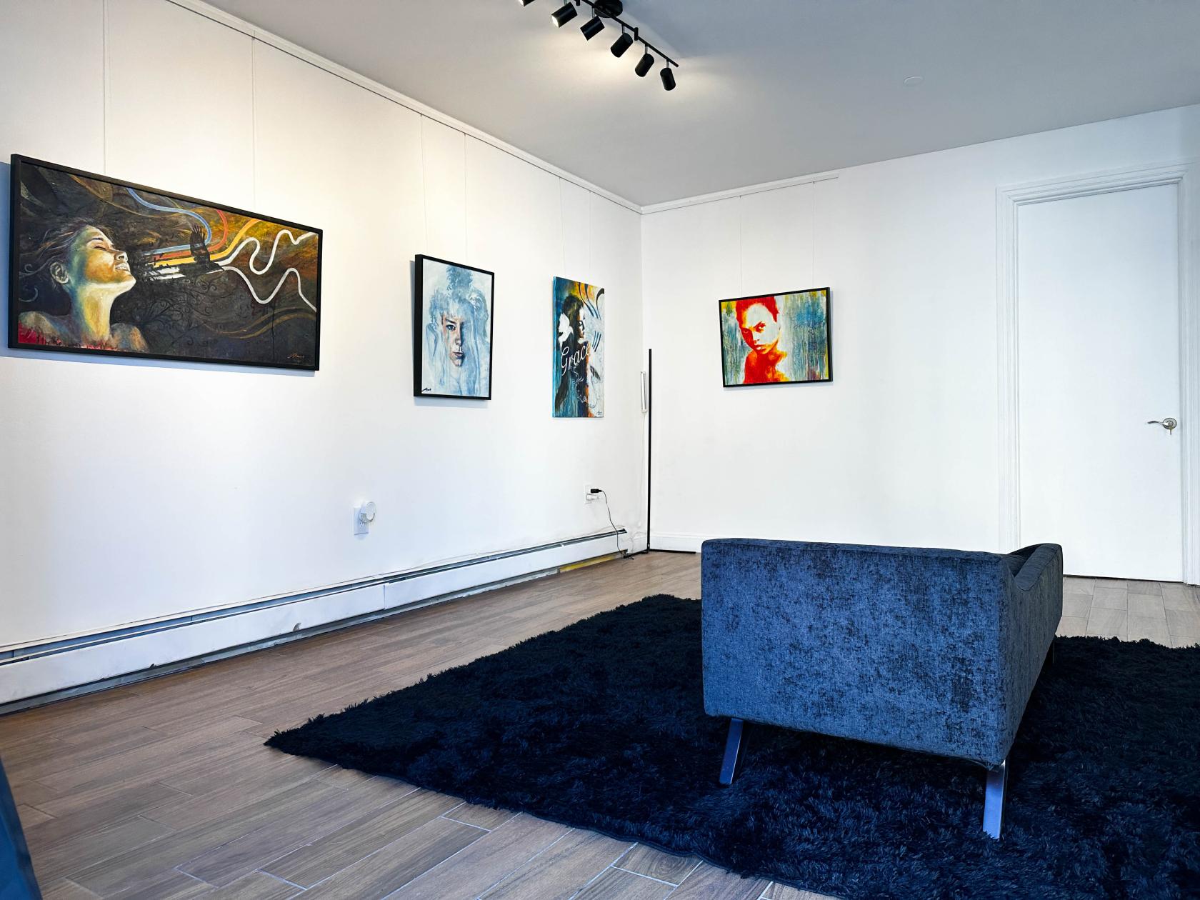 An event venue with white walls, contemporary artwork, wood floors, and a blue sofa at CoCreate.