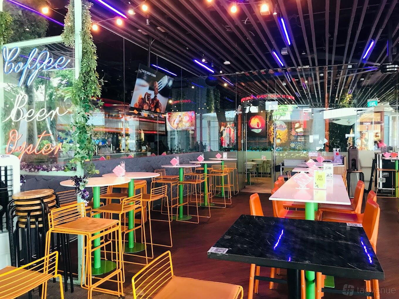 A pub with colorful high tables and stools, neon ceiling lights, and greenery accents at Tipsy Bunny.