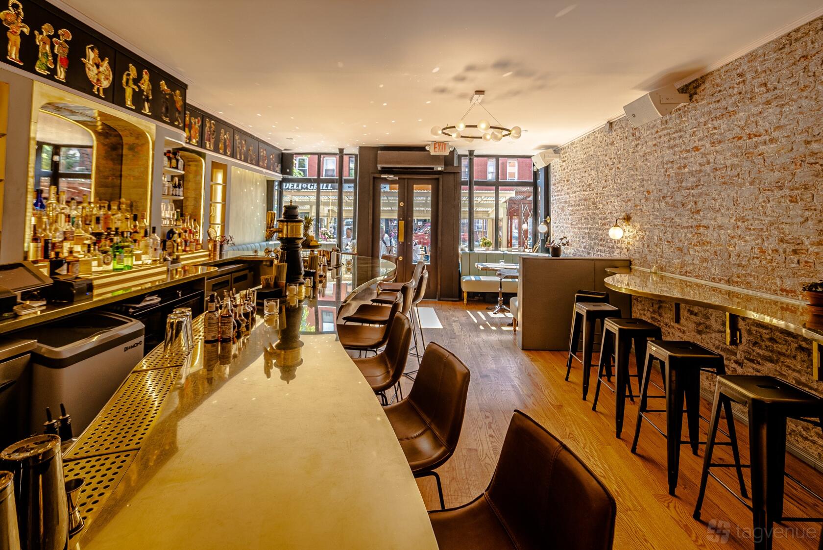 A bar with exposed brick walls, wooden floors, and a marble-topped counter at Little Rascal Greenpoint.