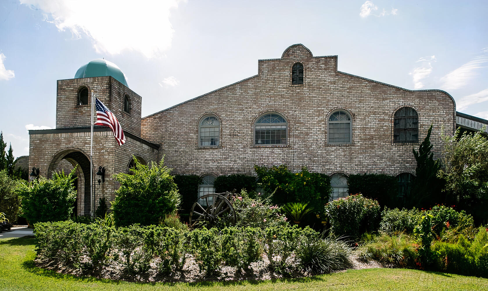 A versatile event space with a brick exterior, arched windows, and garden landscaping at Haak Vineyards & Winery.