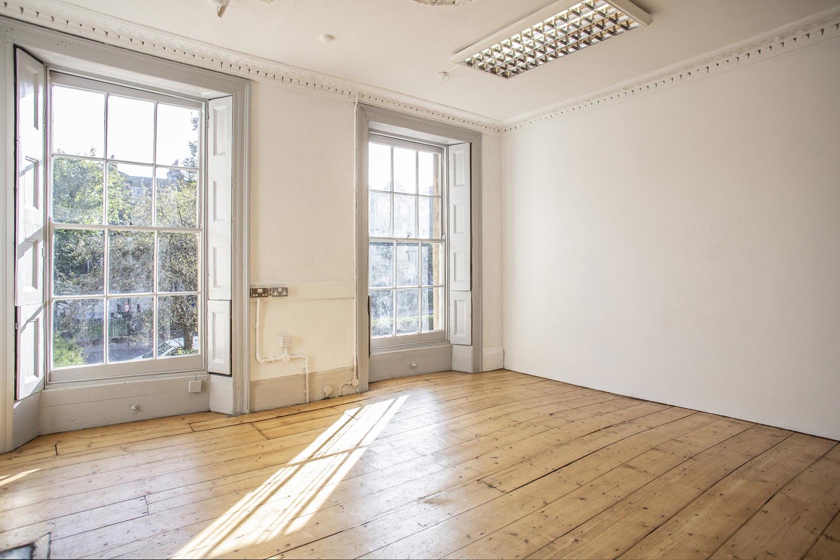 A photo studio with large sash windows, ample natural light, and wood floors at Anomalous Space.
