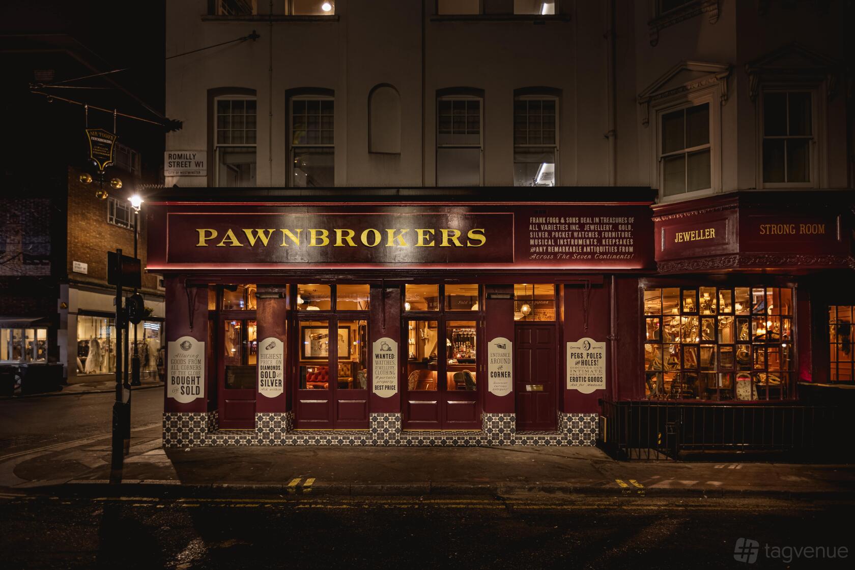 A street-facing pub with large illuminated windows, vintage signage, and dark red exterior at Mr Foggs Pawnbrokers.