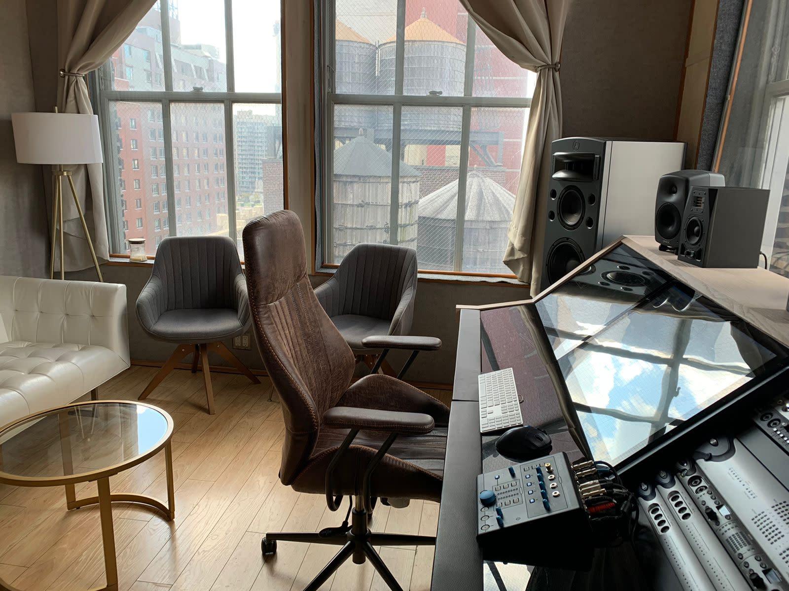 A recording room with studio monitors, mixing console, lounge seating, and large windows at Lounge Studios NYC.
