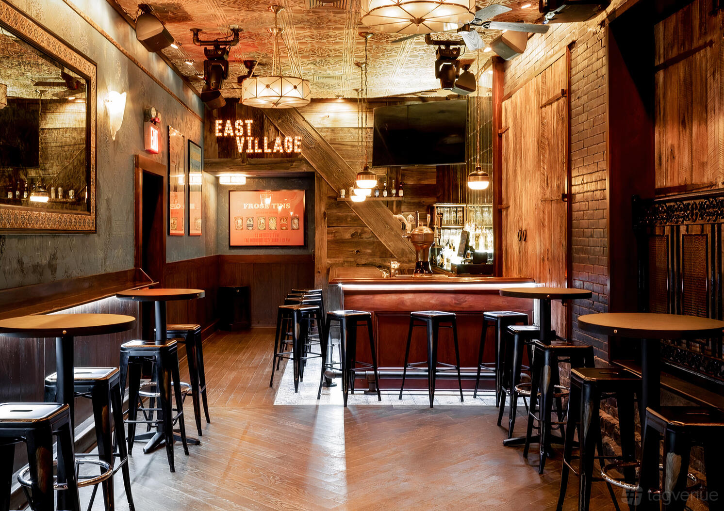 A function room in a bar with high-top tables, vintage decor, wood paneling, and tin ceiling at Downtown Social.