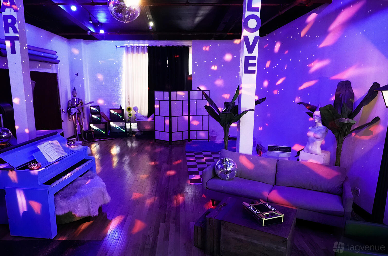 An event space with purple ambient lighting, a blue piano, modern décor, and lounge seating at Elle Studios.