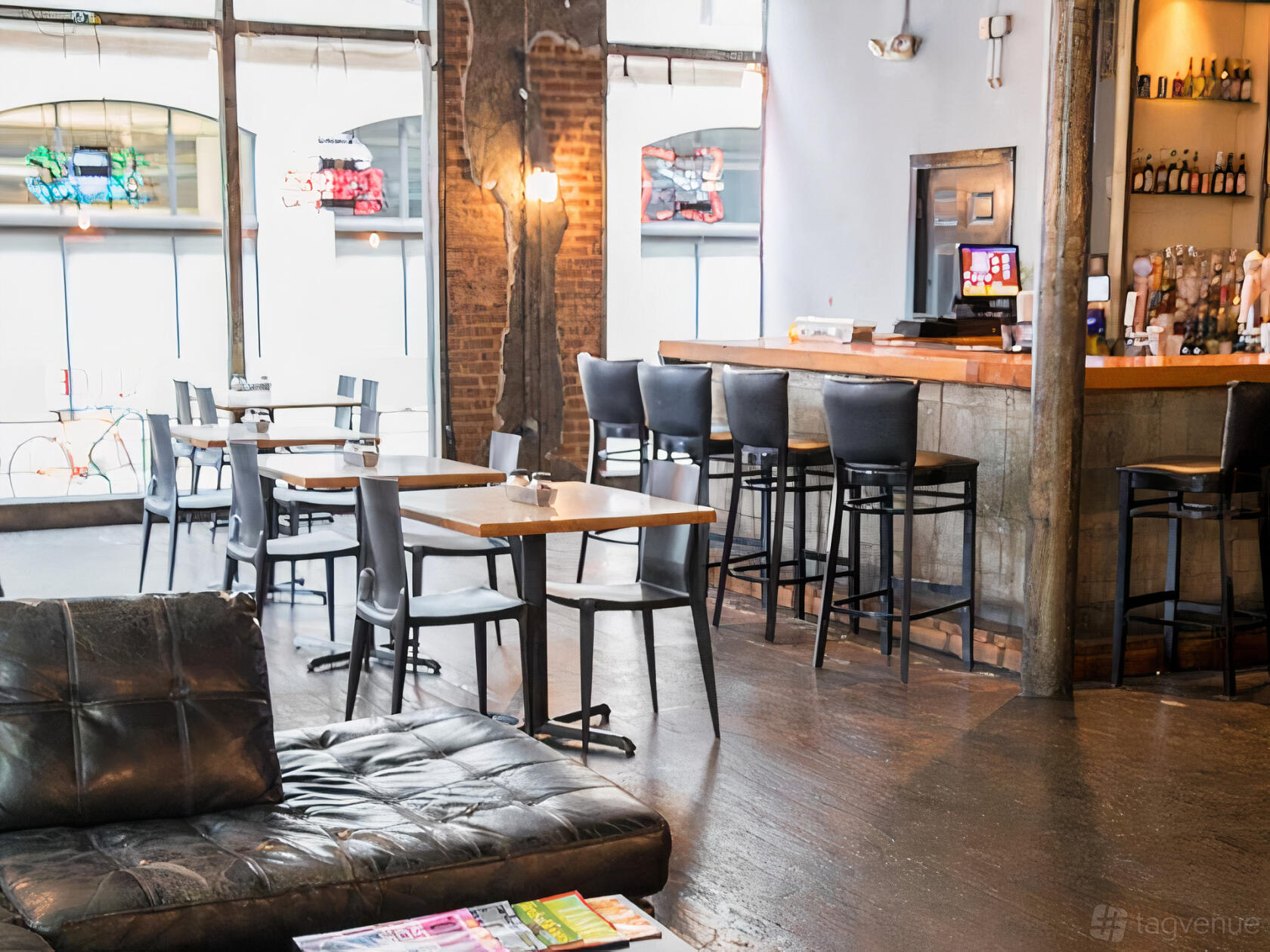 A restaurant with exposed brick walls, high-top tables, and a wooden bar with black stools at Slice Downtown.