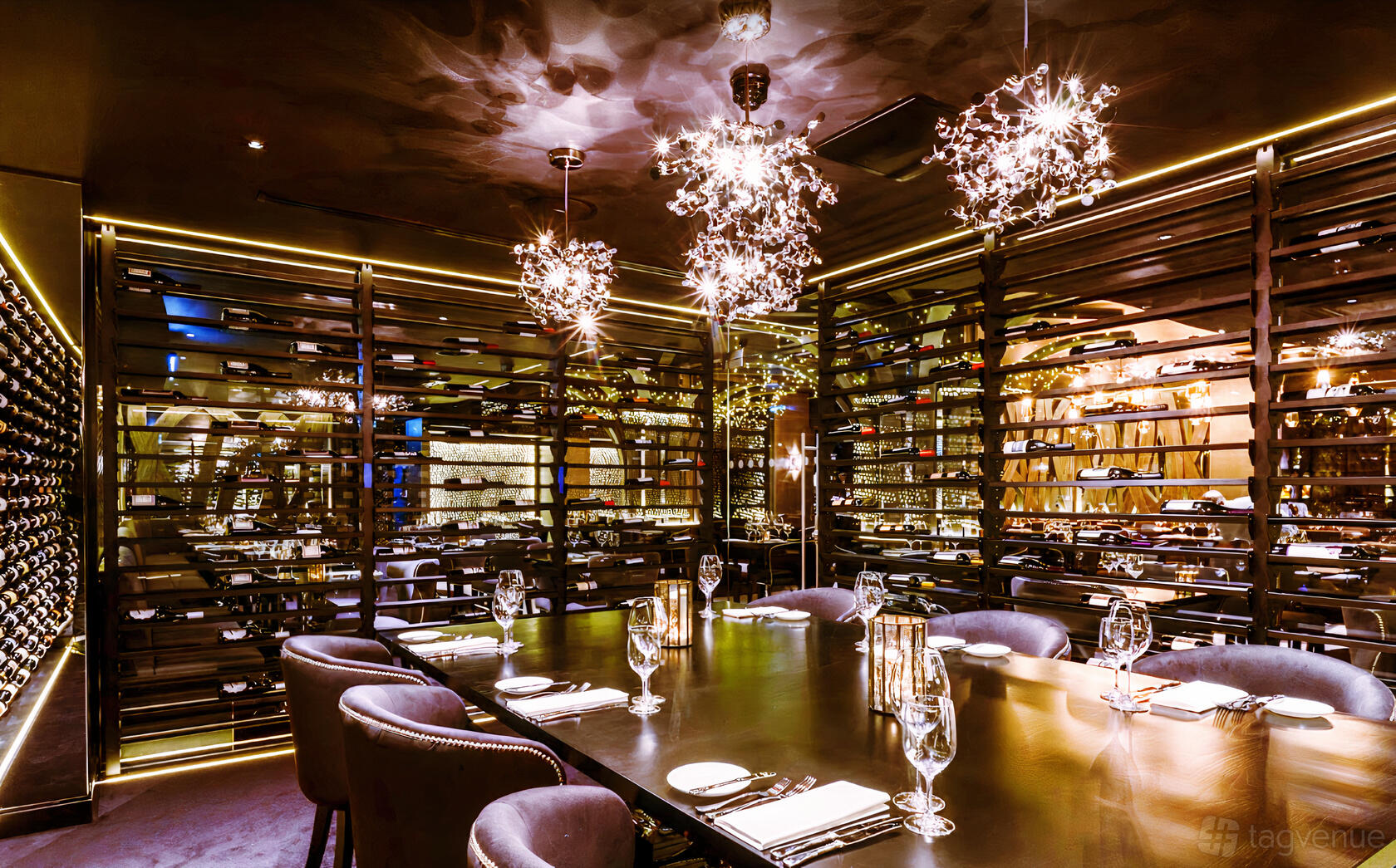 A dining room with a long table, plush chairs, glassware, dramatic lighting, and wine displays at Gaucho Birmingham.