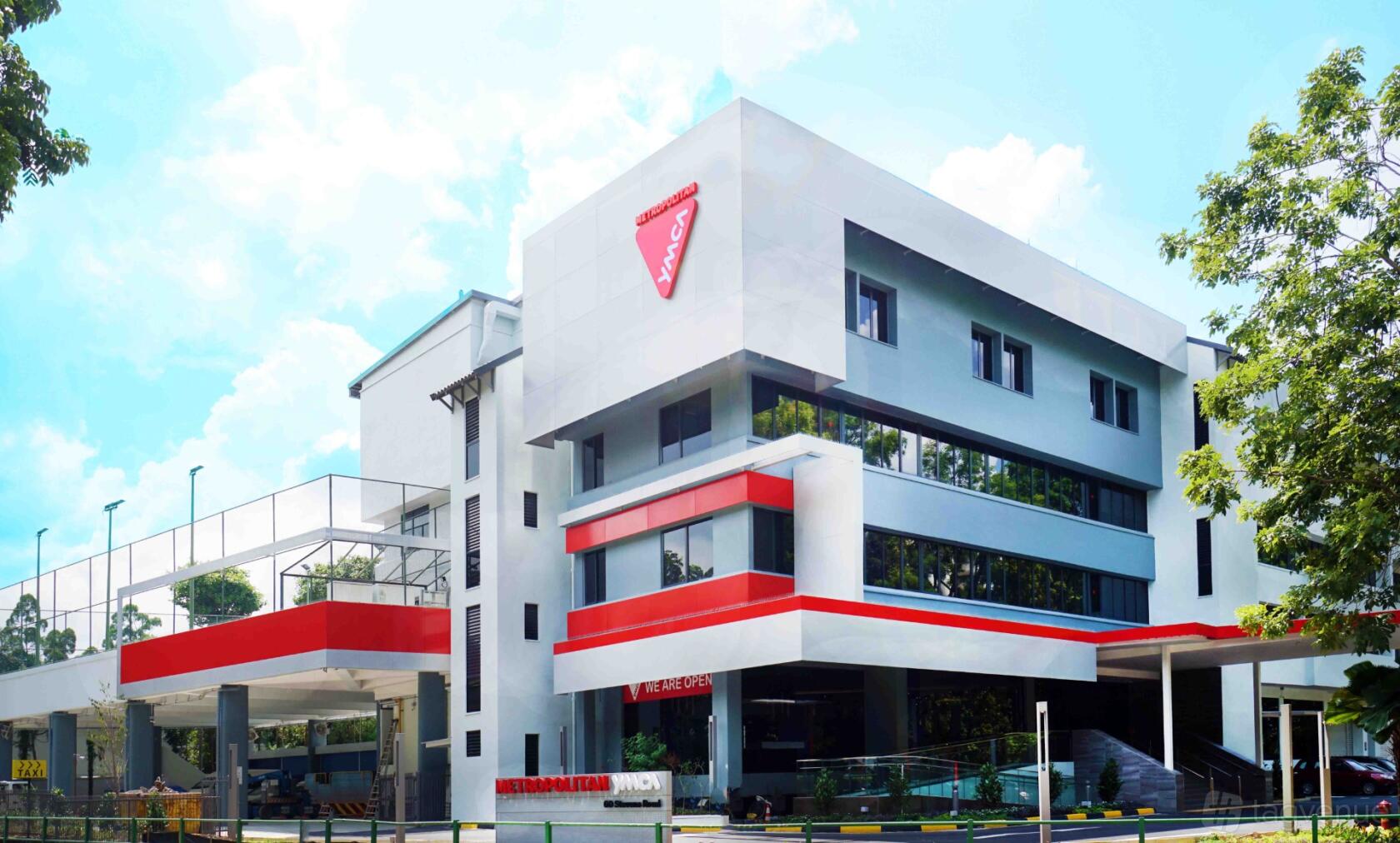 A modern hotel building with red accents, large windows, and the YMCA logo at Metropolitan YMCA Singapore.