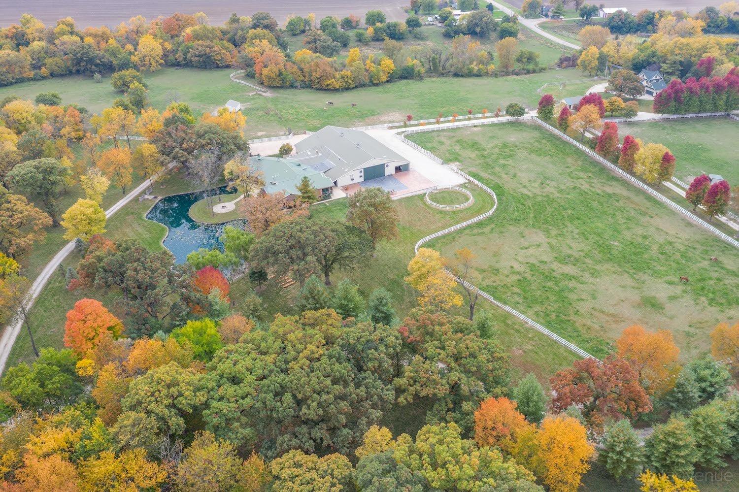 An open air venue with expansive grassy fields, tree-lined paths, and a pond at BrighterDaze.