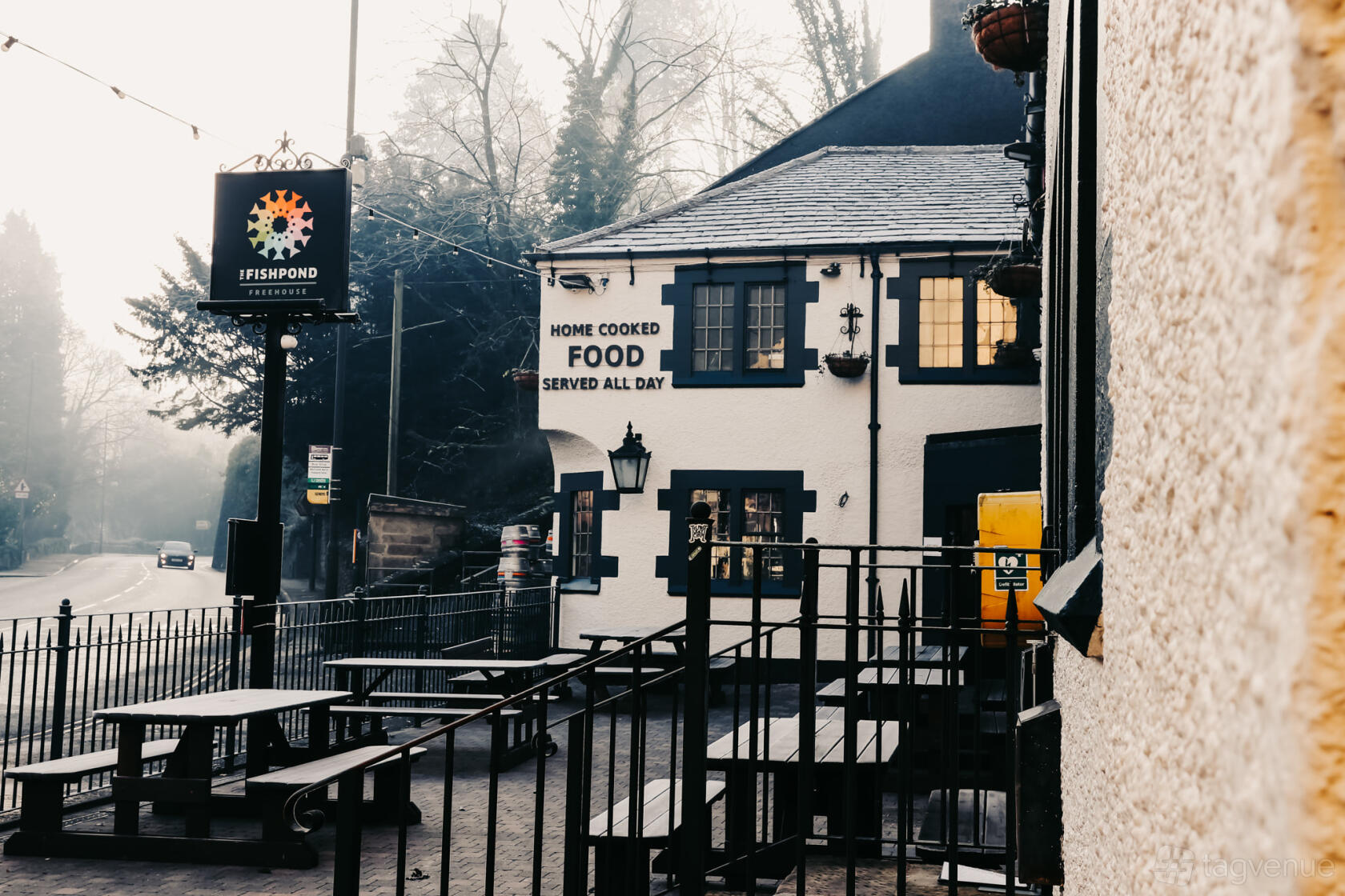 A pub with outdoor picnic tables and a sign advertising home-cooked food at The Fishpond.