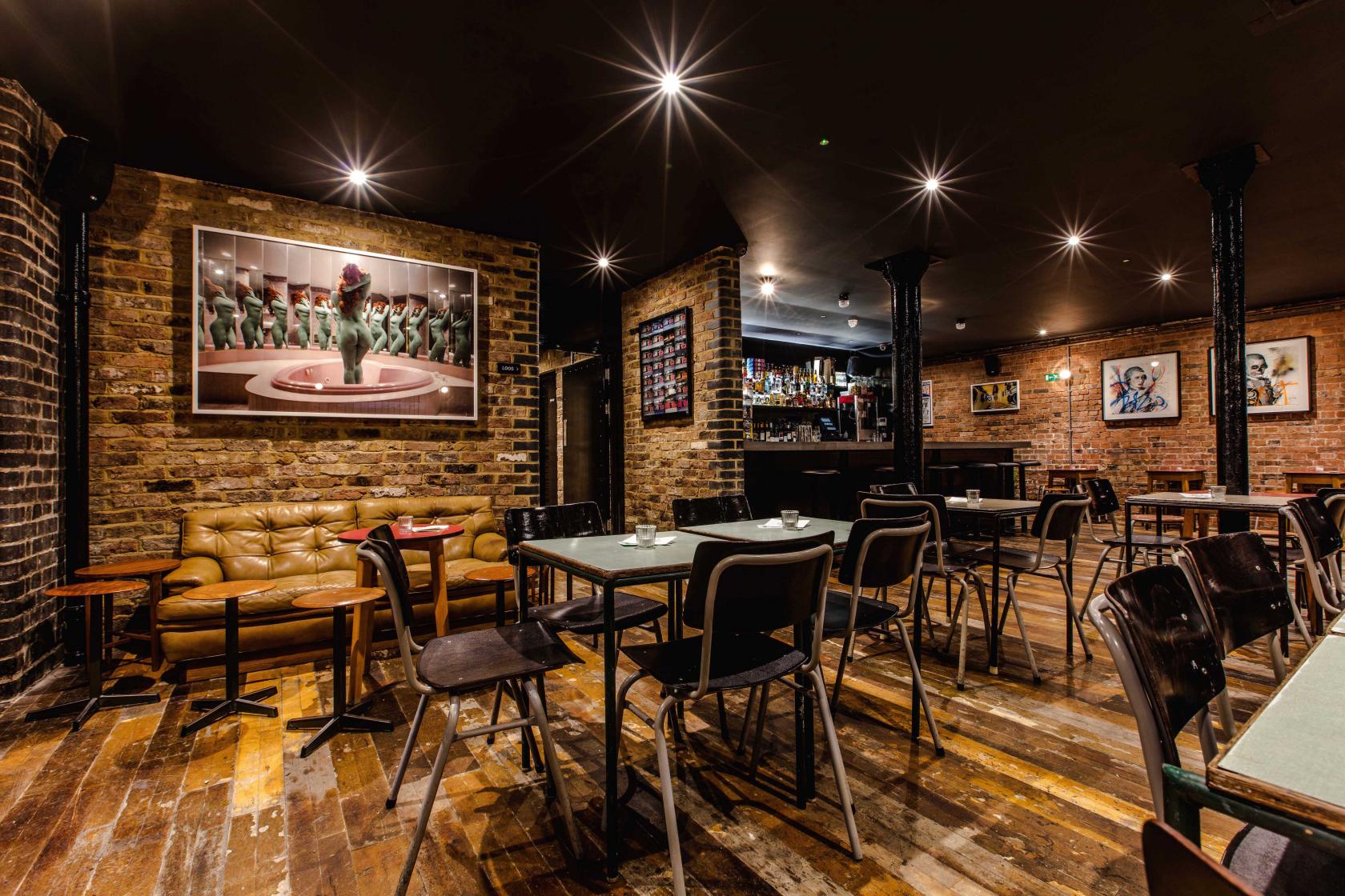 An underground bar with exposed brick walls, wooden floors, and eclectic artwork at Coin Laundry.