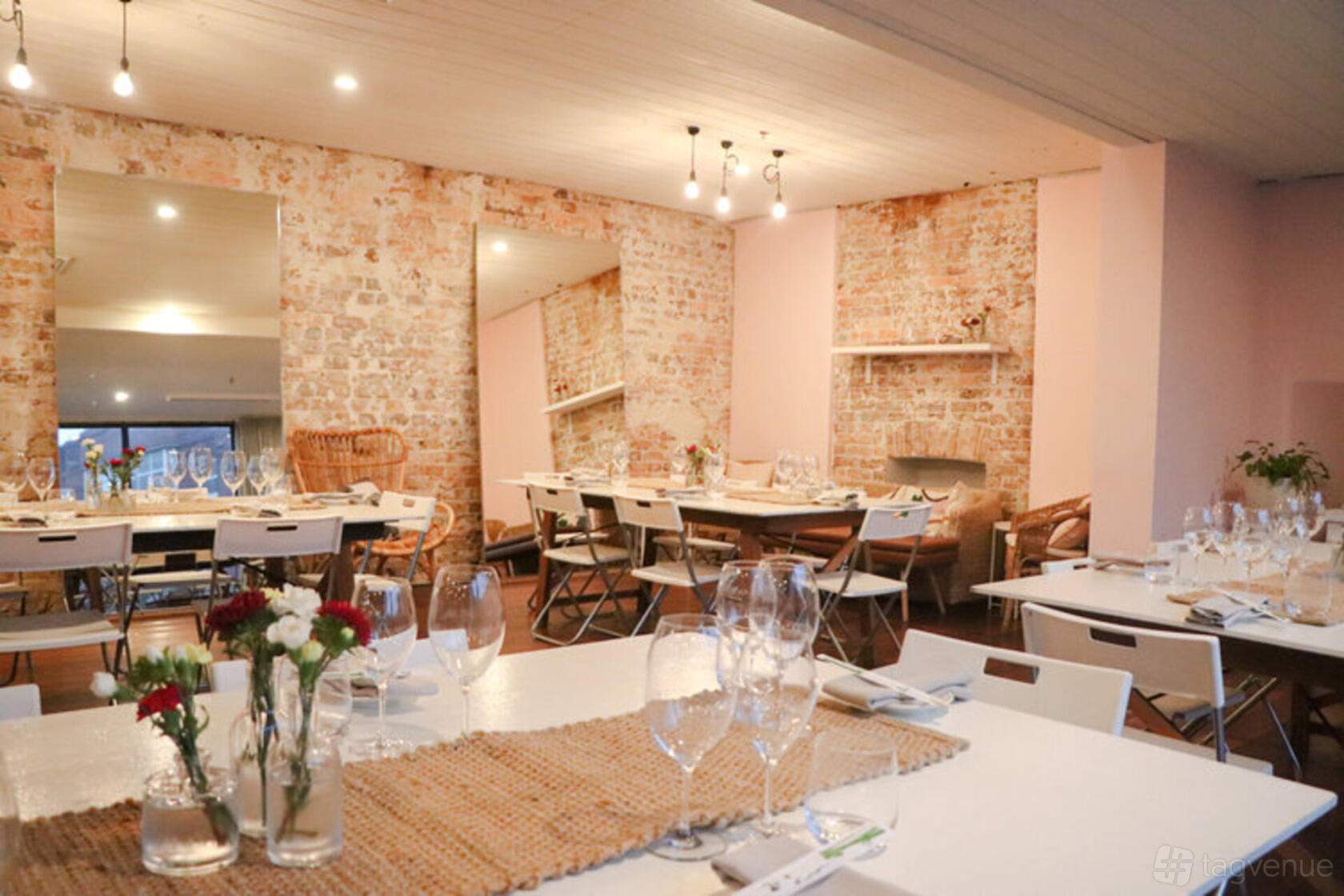A dining room with exposed brick walls, large mirrors, and tables set with glassware at Honkas Bar + Eats.