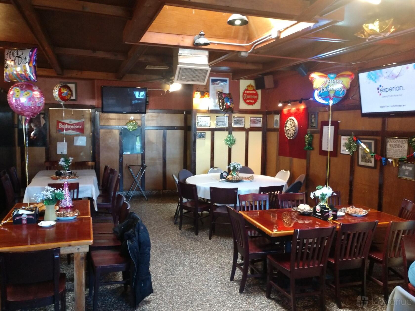 An event space in a pub with wood-paneled walls, round and rectangular tables, and party decorations at The Gather Inn Again.