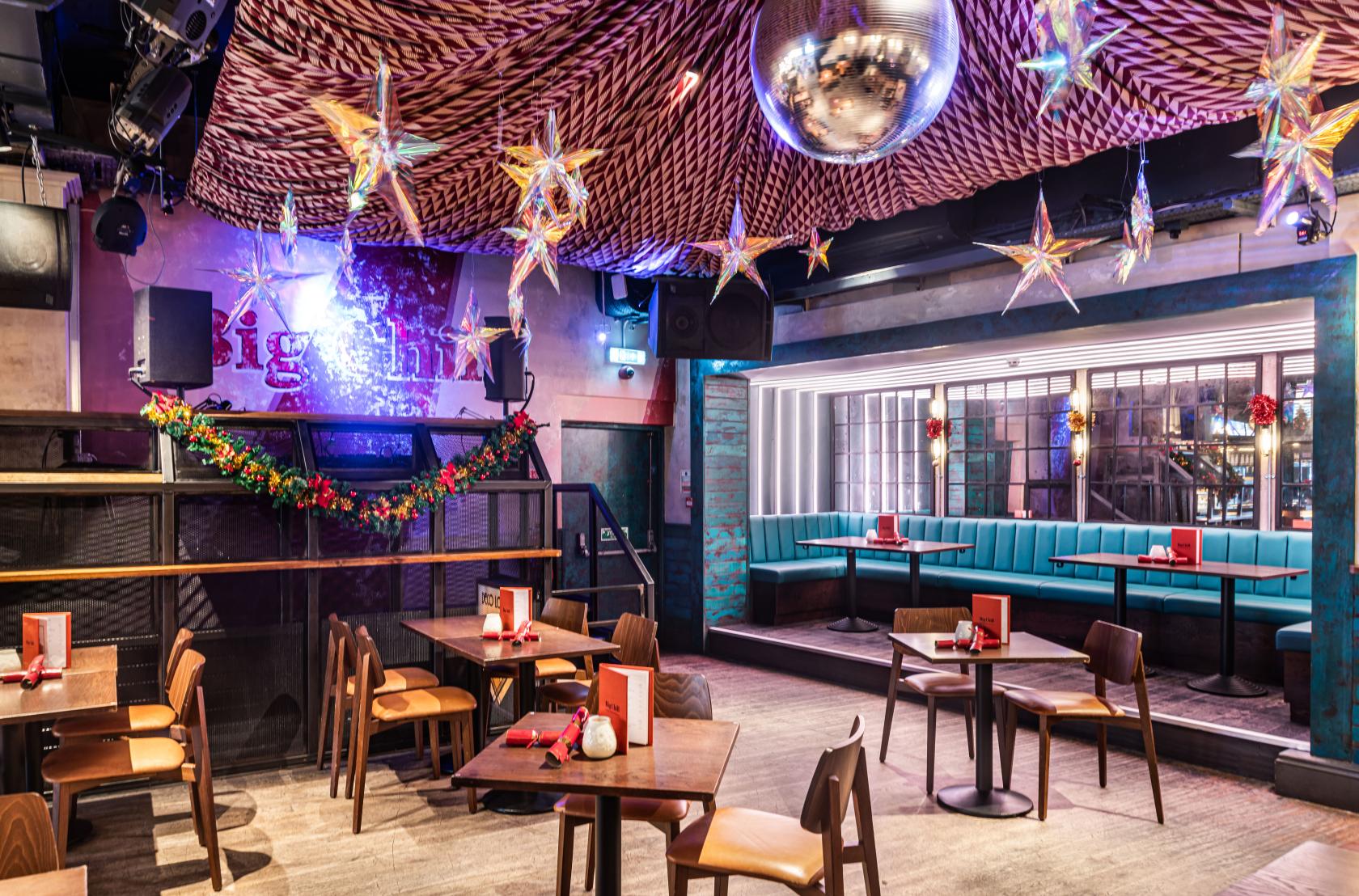 An event space with star-shaped hanging lights, a disco ball, and teal booth seating at Big Chill Kings Cross.