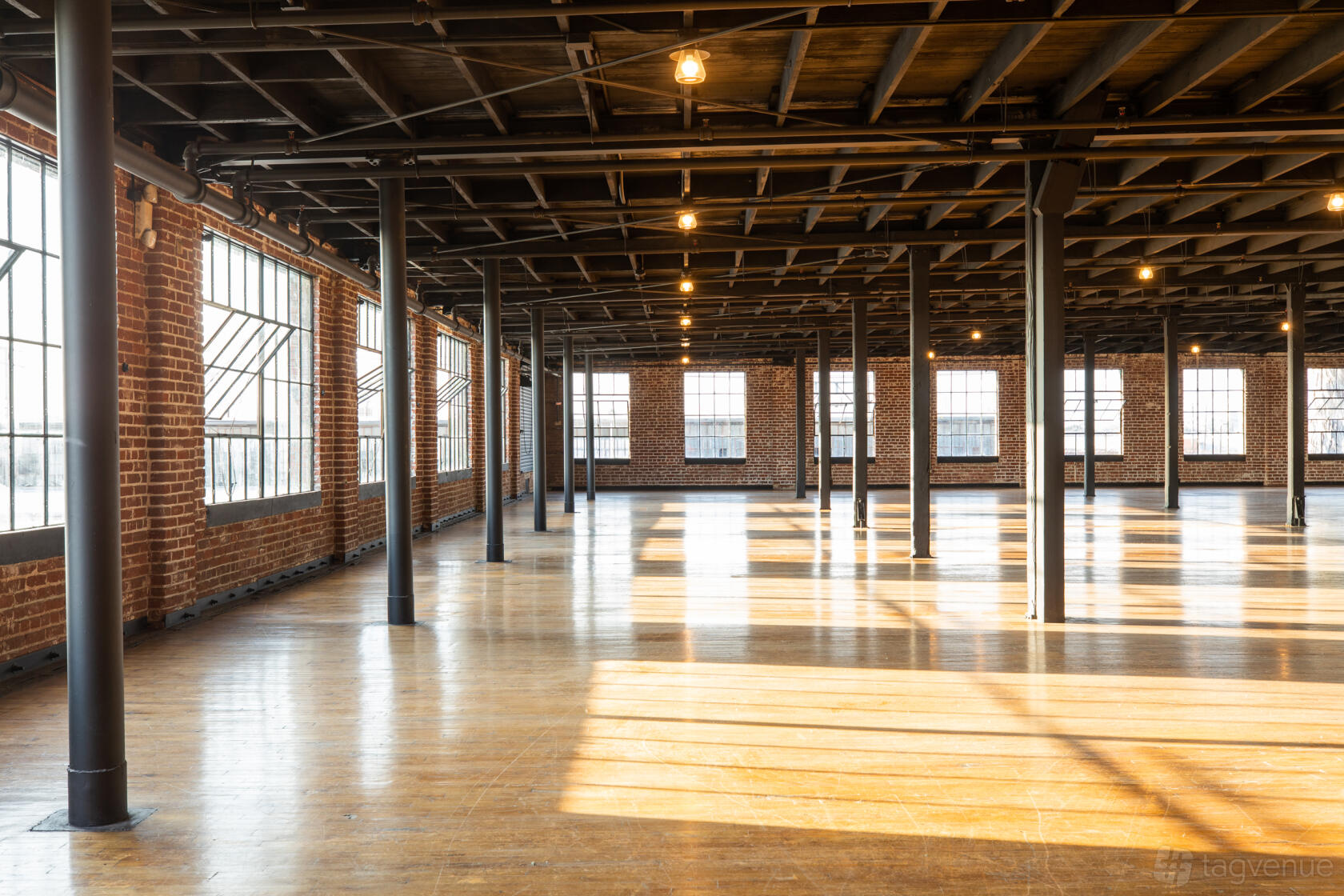 A warehouse with exposed brick walls, large industrial windows, and wooden floors at Versatile Warehouse Complex.
