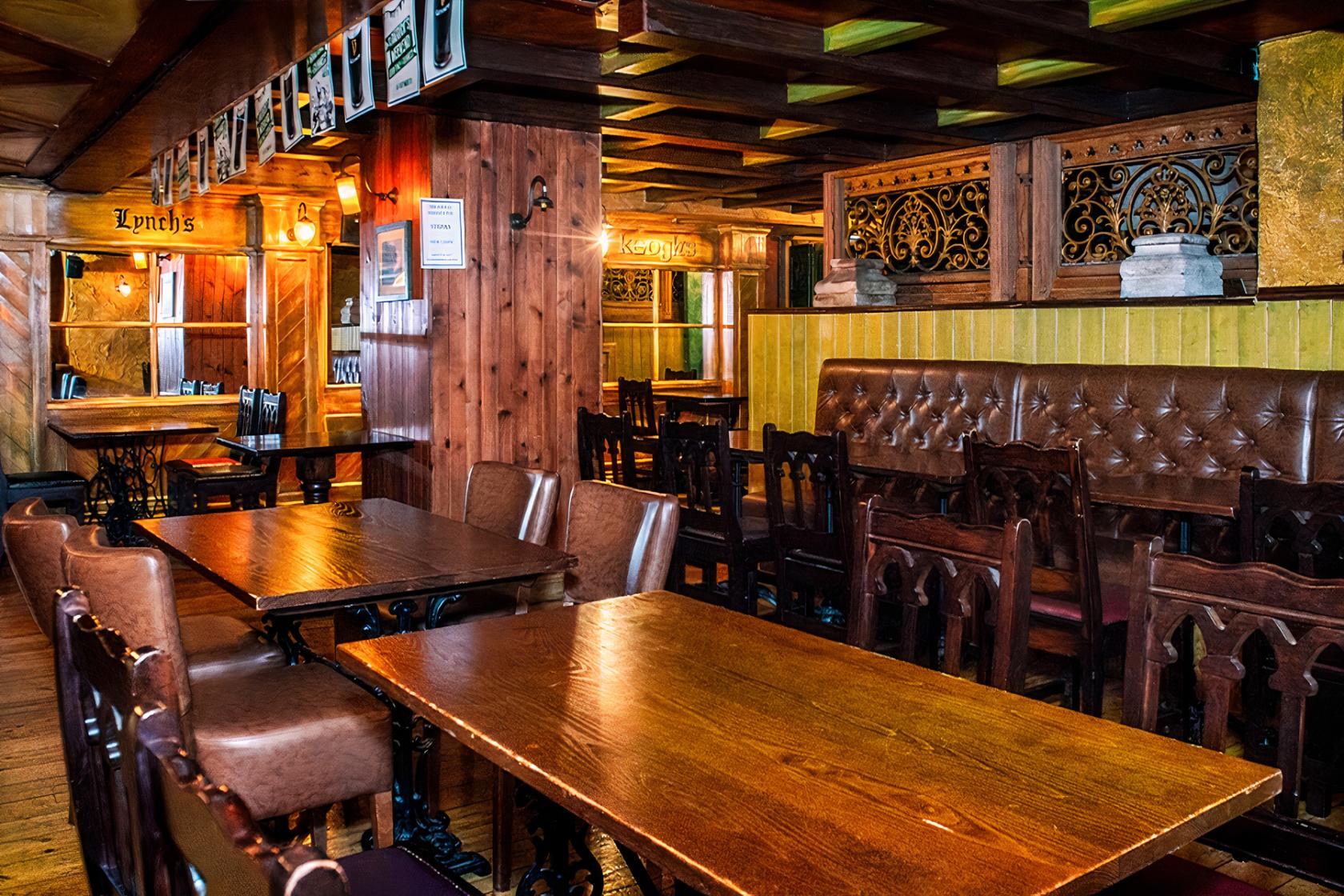 A function room in a pub with wooden tables, leather banquette seating, and ornate wood paneling at Waxy O'Connor's Glasgow.