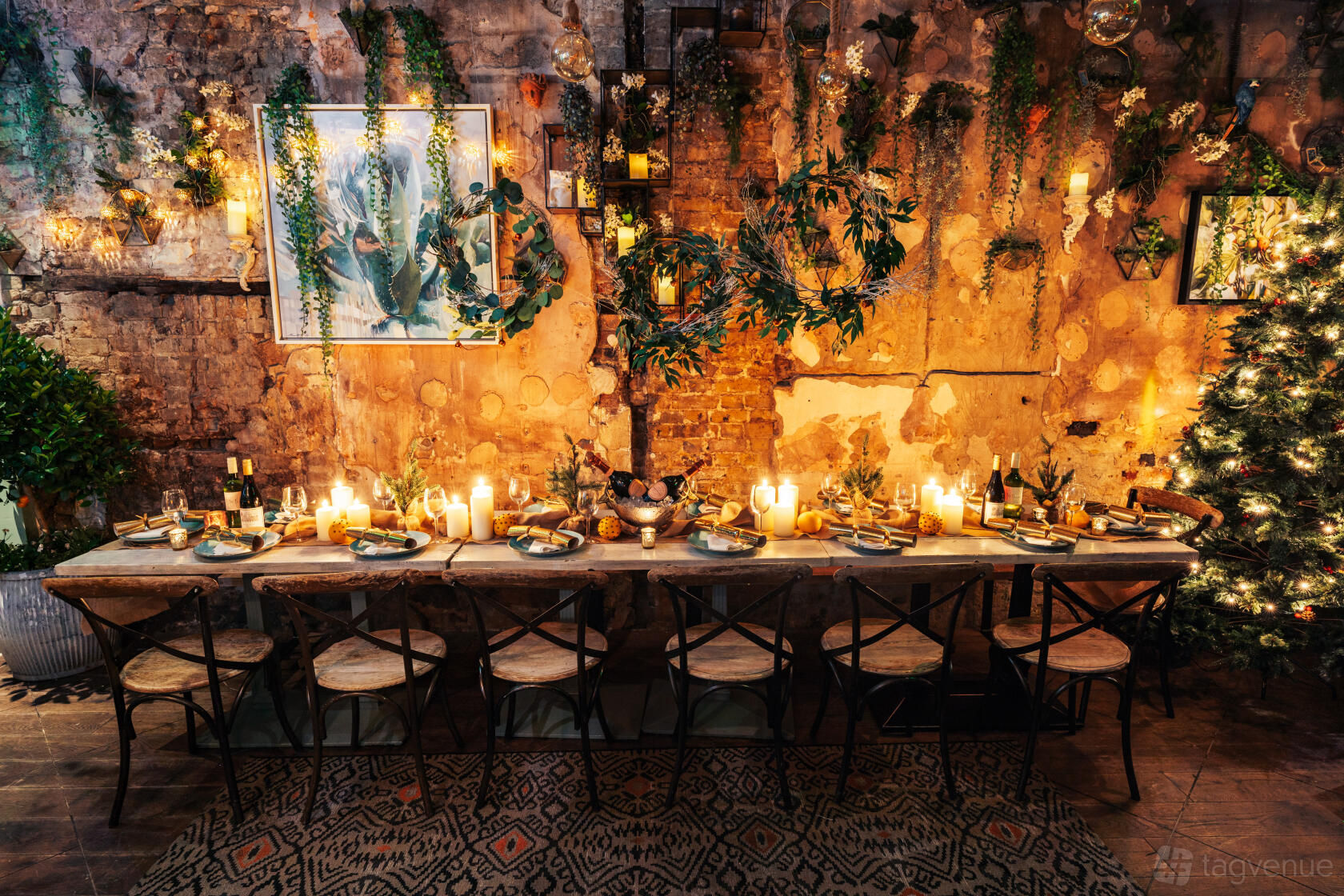 A cocktail bar with a rustic dining table, candlelit setting, exposed brick, and hanging greenery at The Little Orange Door.