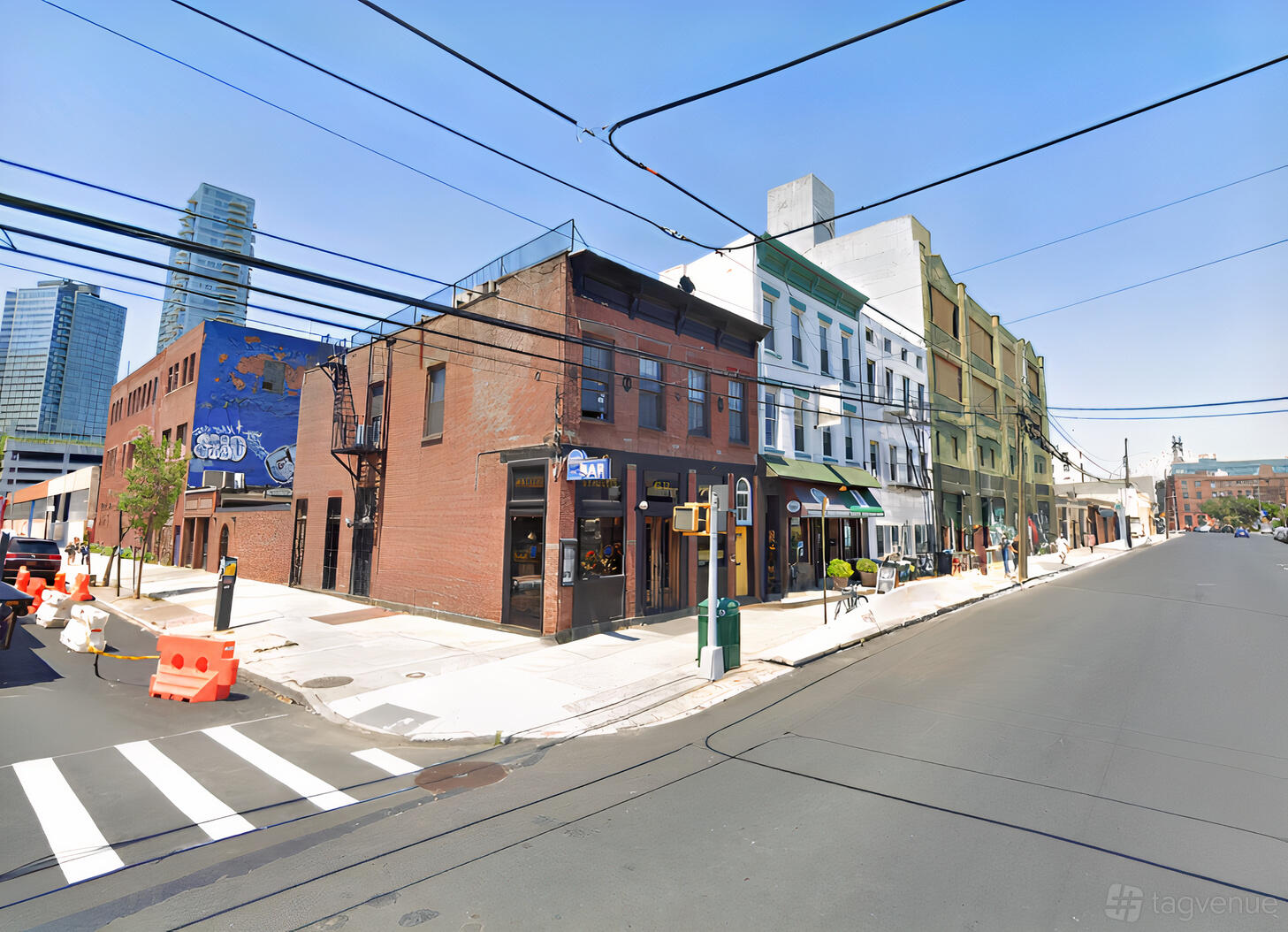 A brick building on a city street corner with large windows and neighboring storefronts at LIC Weddings.