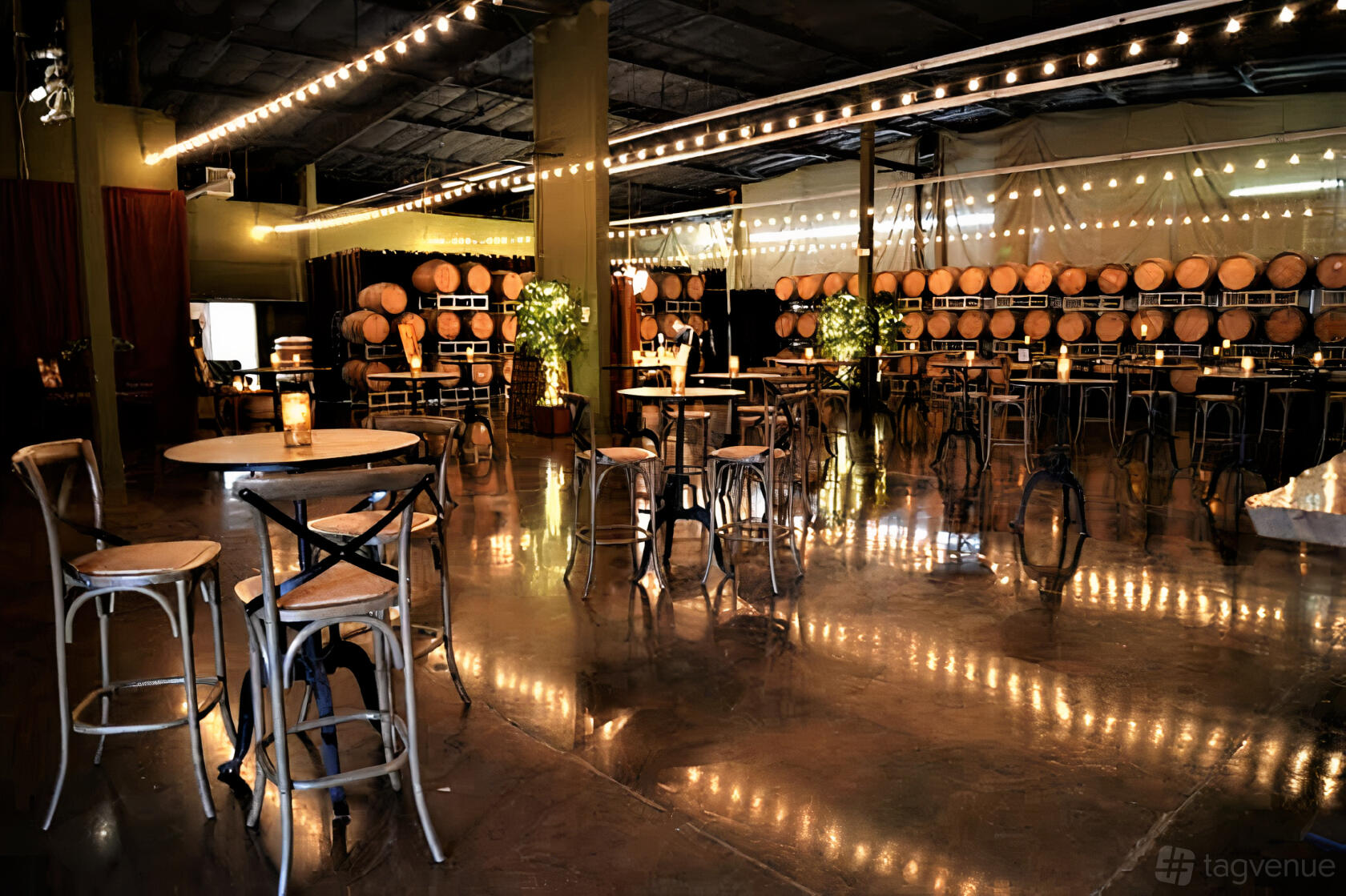 An event venue with wine barrels lining the walls, string lights overhead, and round cocktail tables at Domenico Winery.