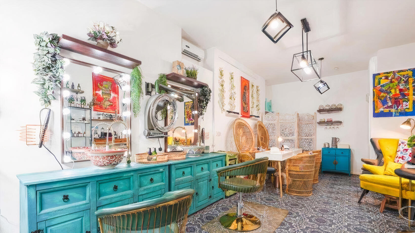 An event venue with turquoise sideboards, vanity mirrors with lights, green chairs, and decorative wall hangings at Voguish Space for Events & Photos.