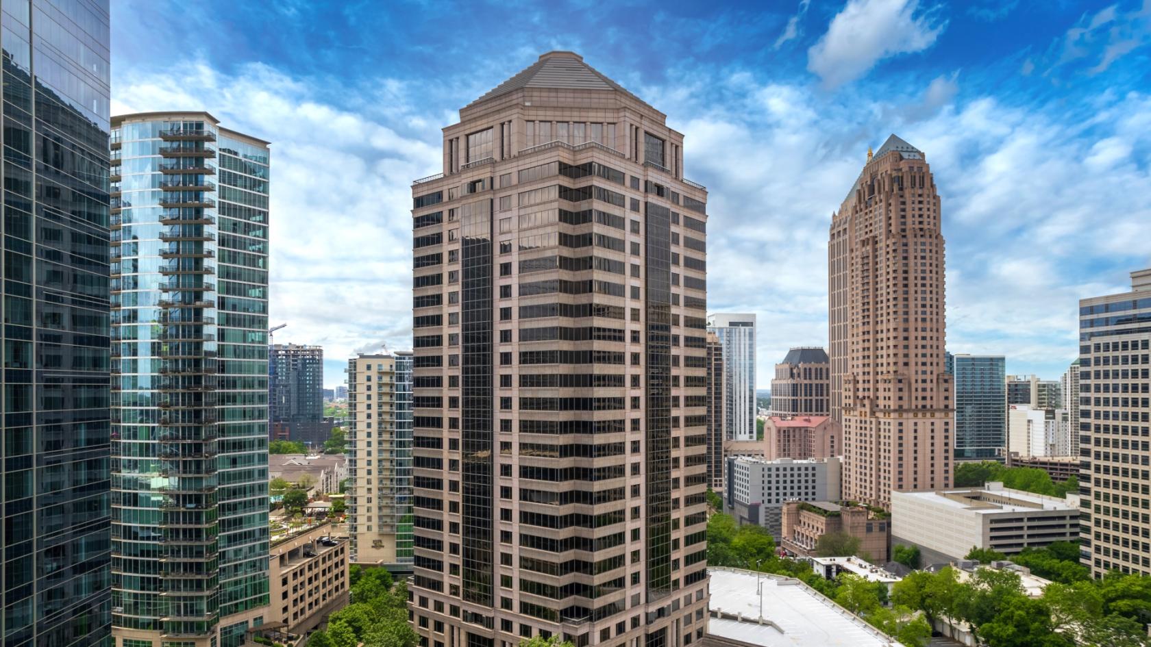 A coworking space with a high-rise office tower surrounded by modern skyscrapers at Peachtree Offices Midtown.
