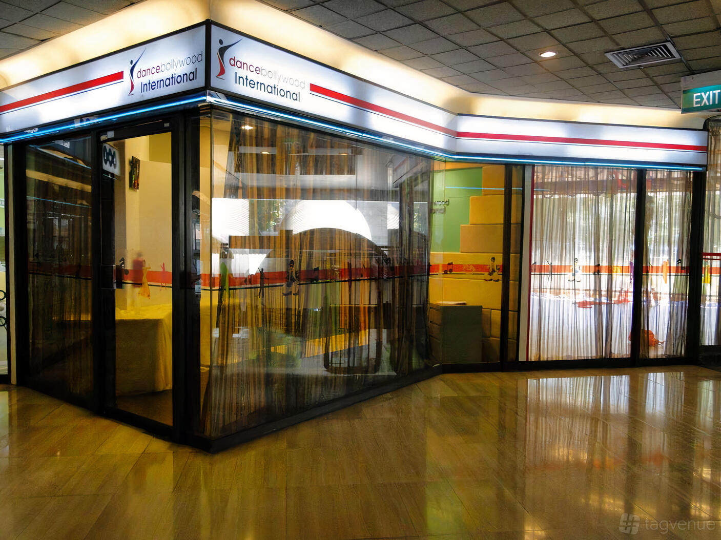 A dance studio with mirrored walls, glass partitions, and polished wooden floors at Dance Bollywood International.