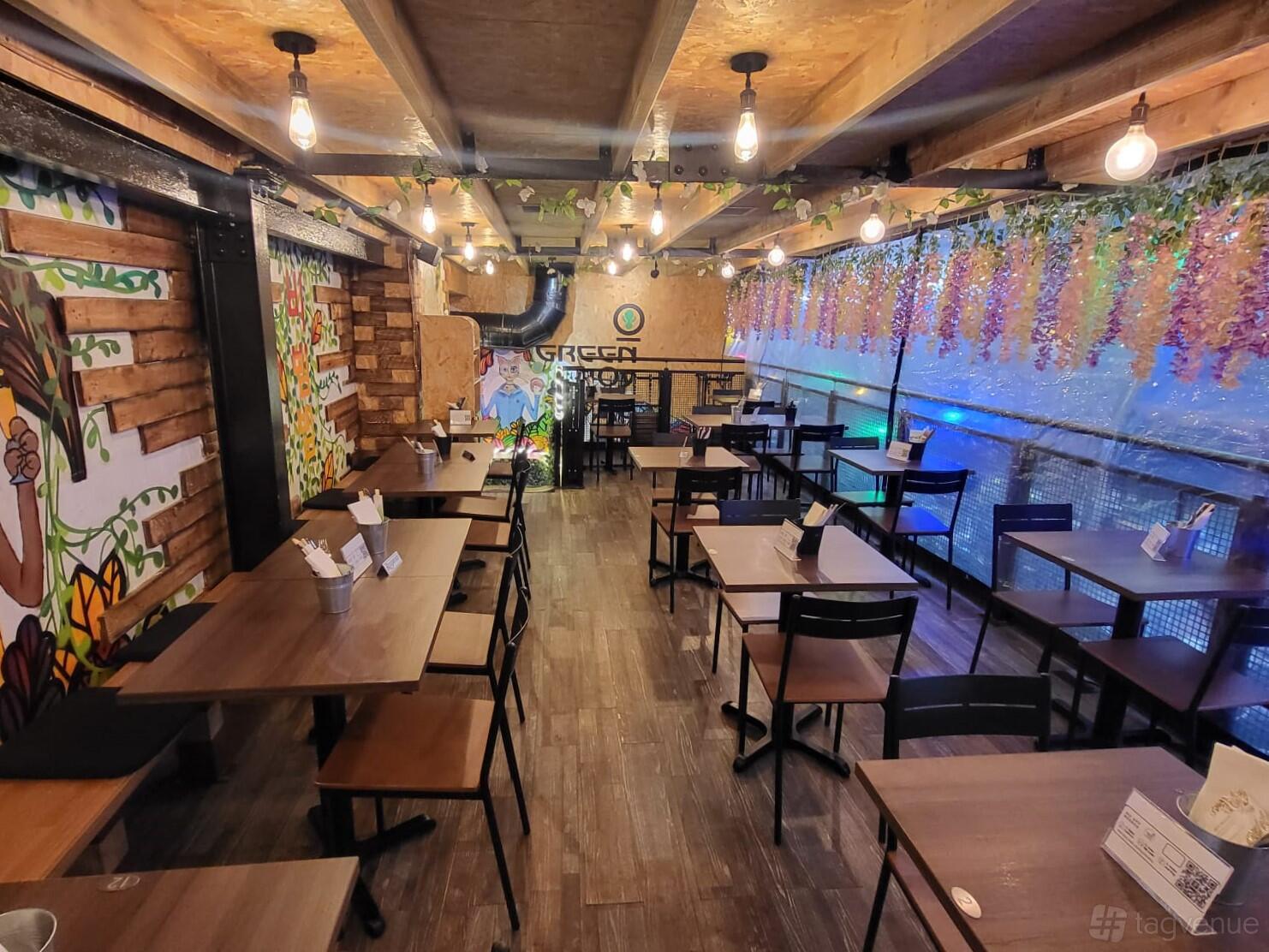 A dining room with wooden tables, string lights, floral ceiling decor, and mural walls at Green Choy - Tooting.