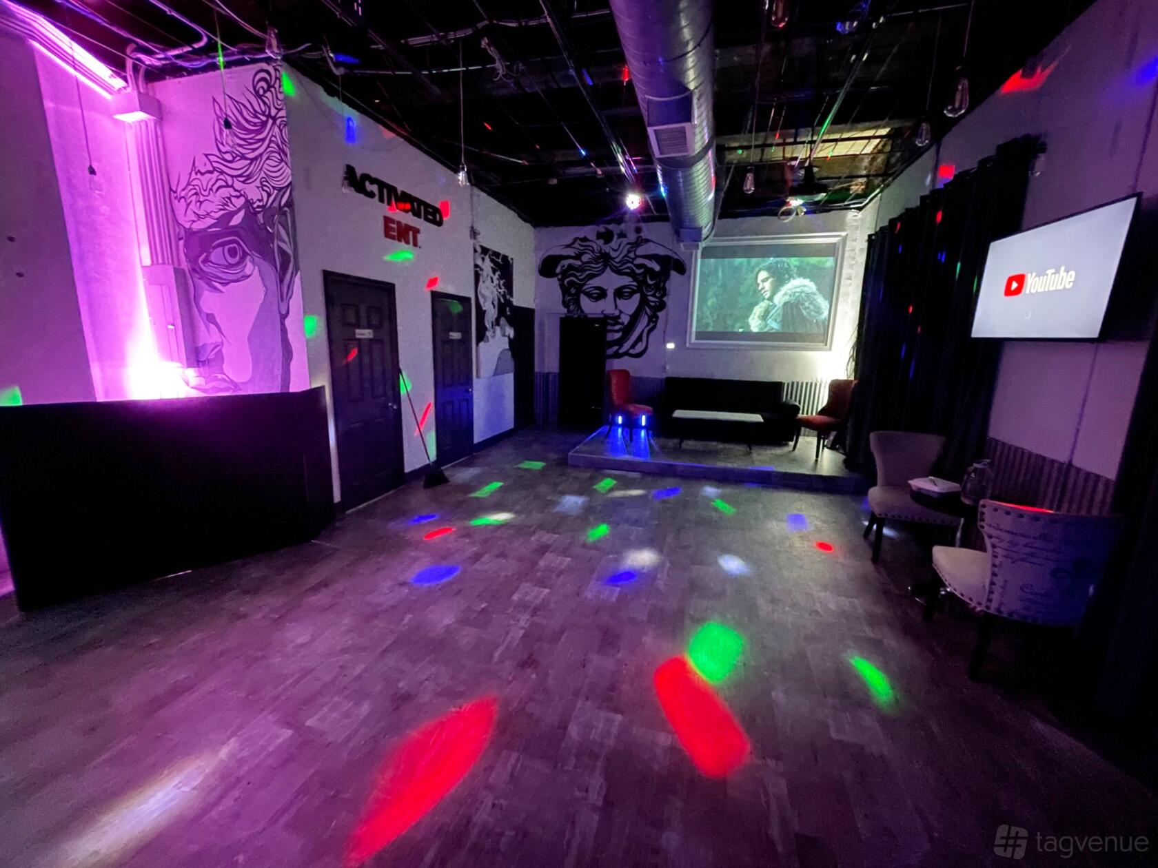 An event venue with colorful dance floor lighting, wall murals, and lounge seating at Activated Studios.