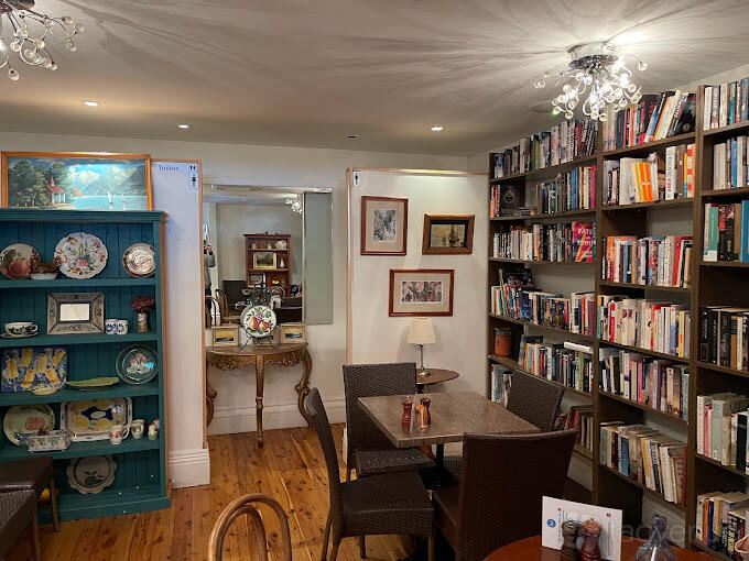A cozy restaurant space with bookshelves, framed art, and a small dining table at Billi's Cafe.