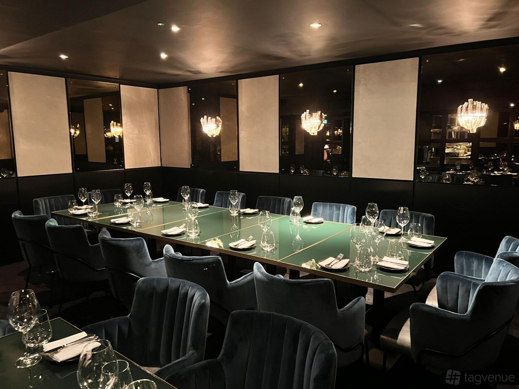 A dining room with a long glass table, velvet chairs, mirrored walls, and chandeliers at Gaucho Chancery Lane.